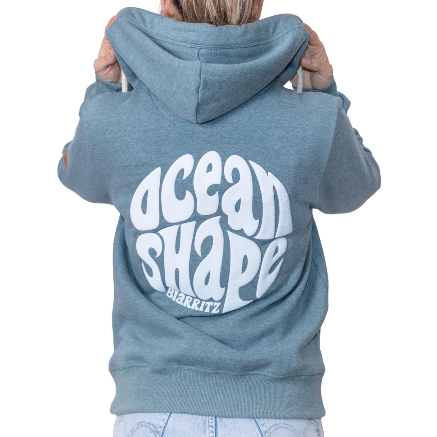 Sweat unisexe à capuche vert emeraude avec gros logo bubble "Ocean Shape Biarritz" ecru dans le dos, vu de dos sur mannequin femme