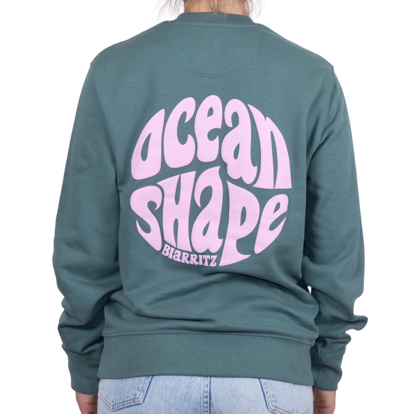 Sweat unisexe sans capuche Green Bay avec grand logo bubble "ocean shape biarritz" rose pâle dans le dos, vu de dos sur mannequin femme.