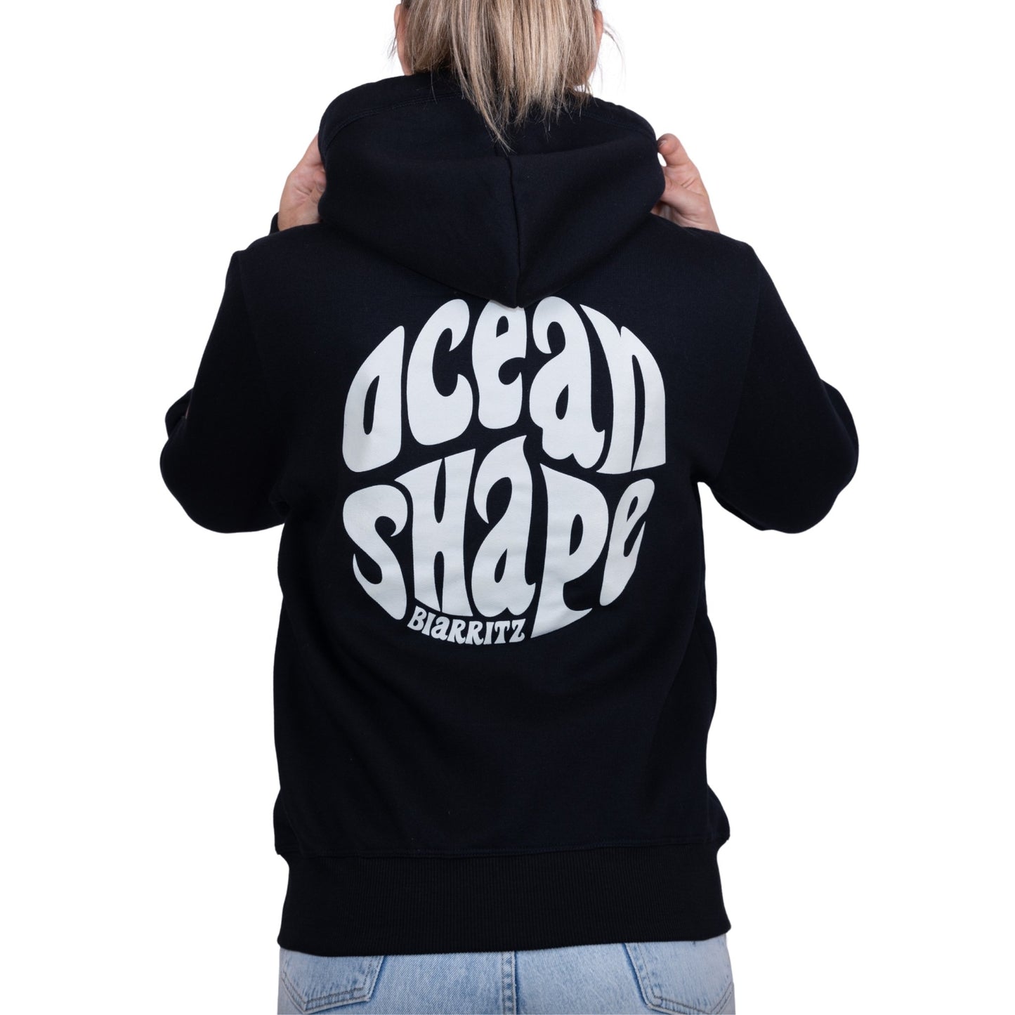 Sweat unisexe à capuche noir avec gros logo bubble "Ocean Shape Biarritz" blanc dans le dos, vu de dos sur mannequin femme