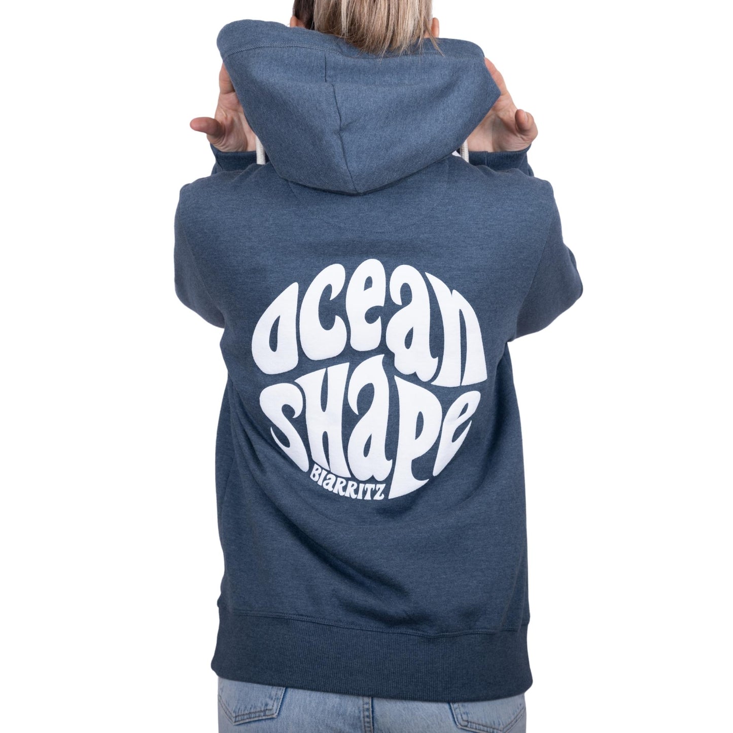 Sweat unisexe à capuche bleu ocean avec gros logo bubble "Ocean Shape Biarritz" blanc dans le dos, vu de dos sur mannequin femme