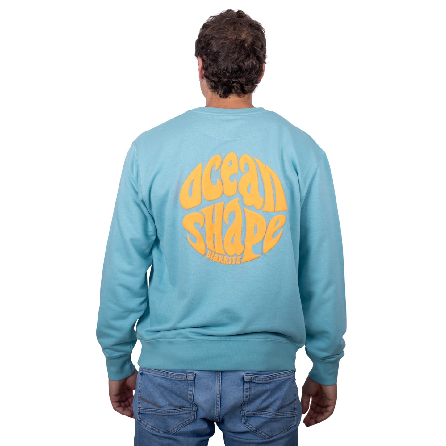 Sweat unisexe sans capuche Teal Monstera avec grand logo bubble "ocean shape biarritz" orange fluo dans le dos, vu de dos sur mannequin homme.
