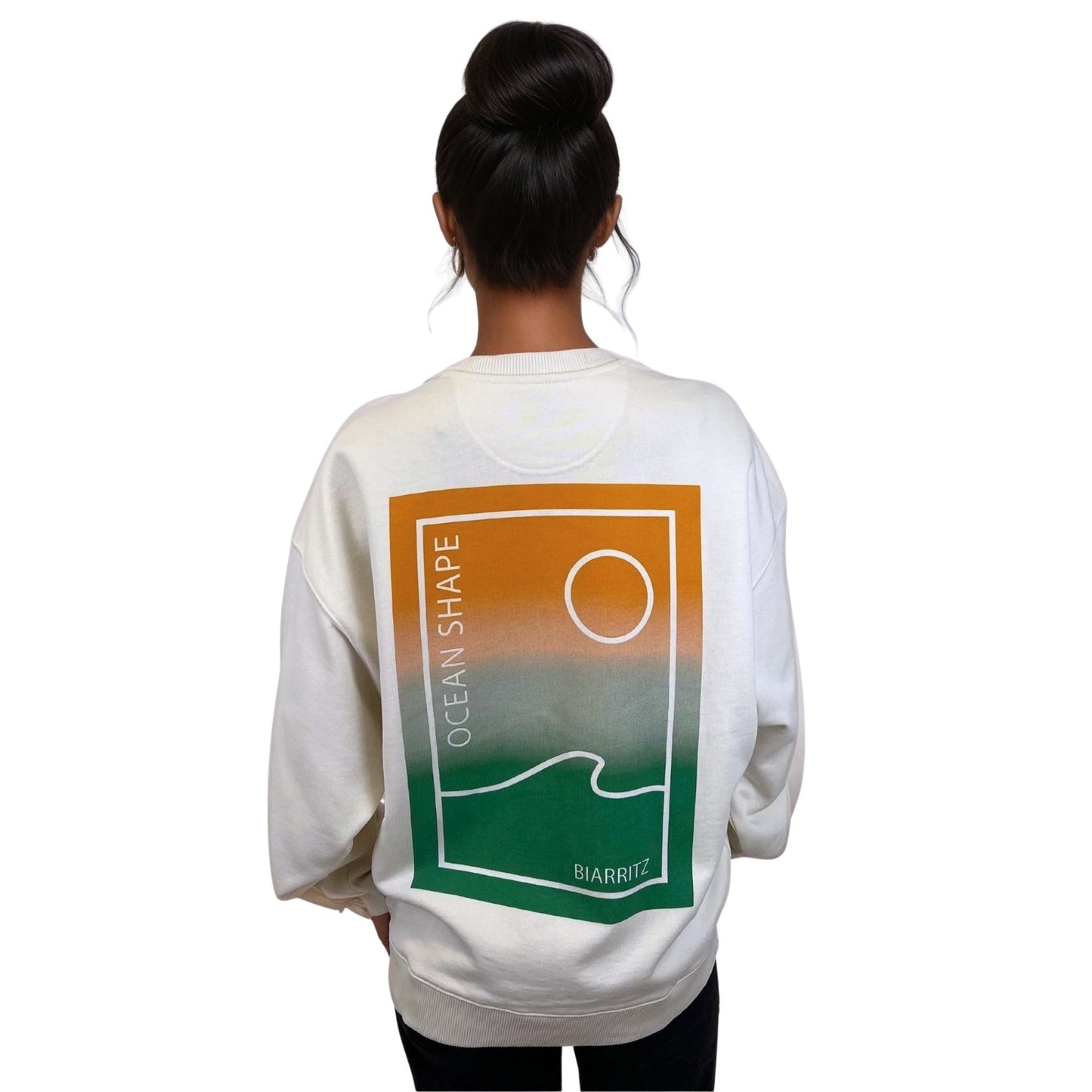sweat à col rond unisexe ocean shape avec une vue sur un mannequin femme de dos, de couleur écru.
avec grand motif minimaliste d'une vague et d'un soleil en dégradé de couleur vert et orange.