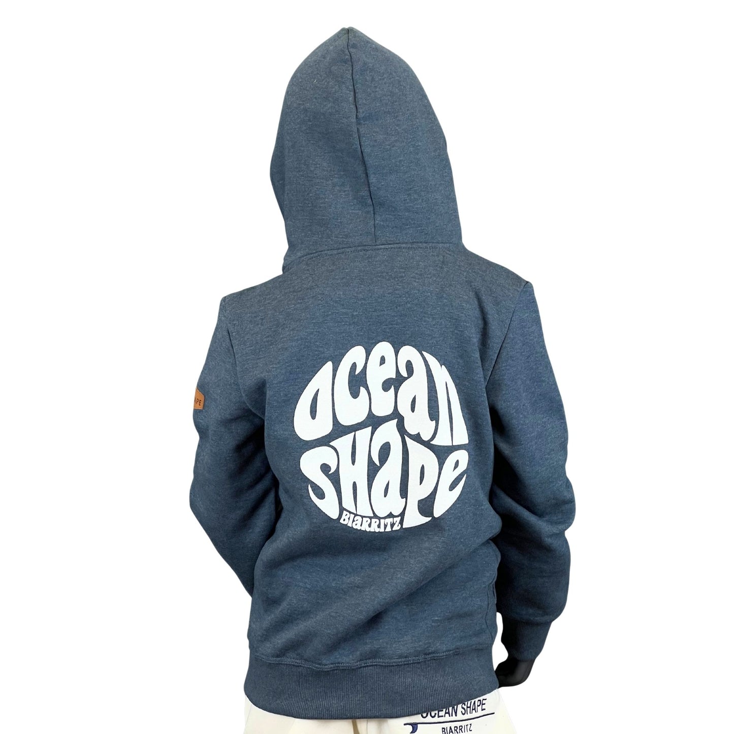 sweat à capuche unisexe enfant de couleur bleu océan, vu sur un mannequin enfant de dos.
Dos : logo bubble ocean shape biarritz en relief et en grand dans le dos.
Le mannequin porte également une casquette.