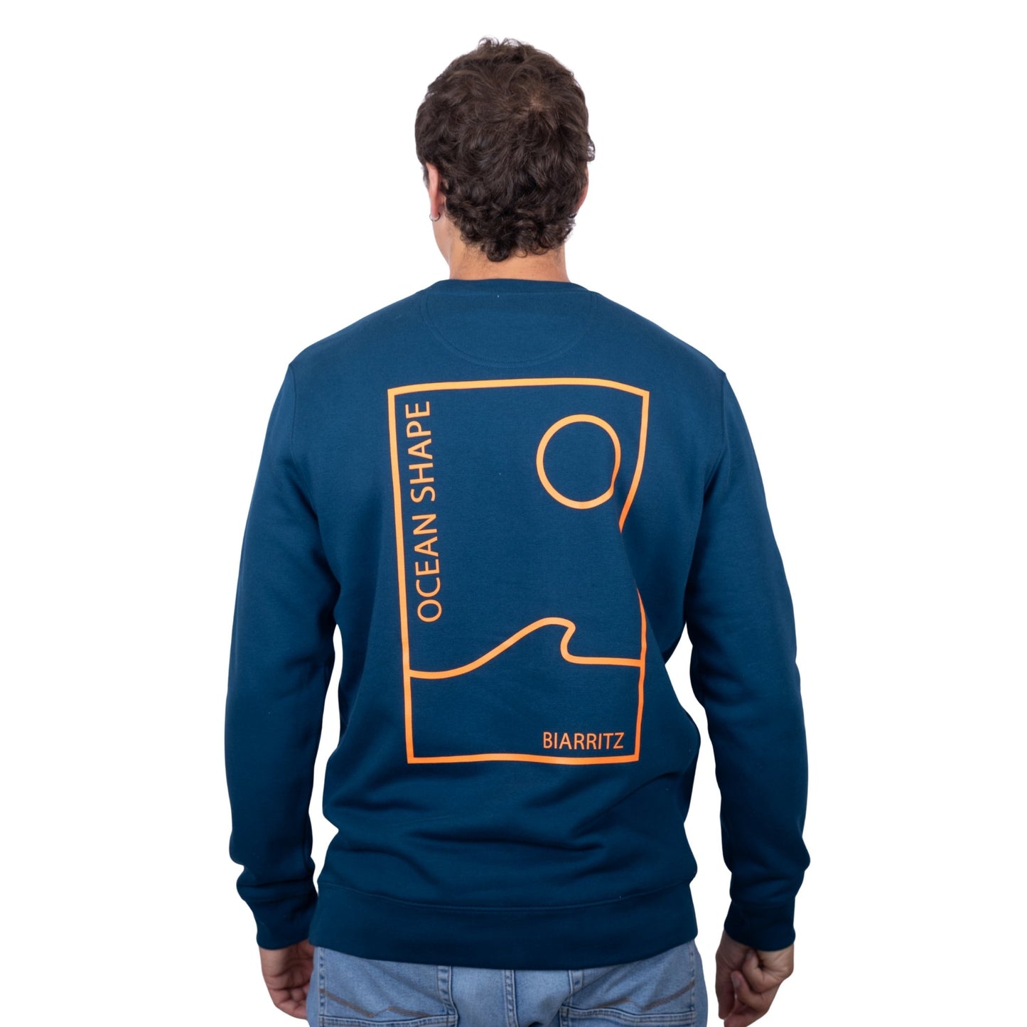 sweat unisexe bleu petrole en coton biologique avec grand encadré vague / soleil minimaliste + écriture "ocean shape Biarritz" orange fluo dans le dos, vu de dos sur mannequin homme