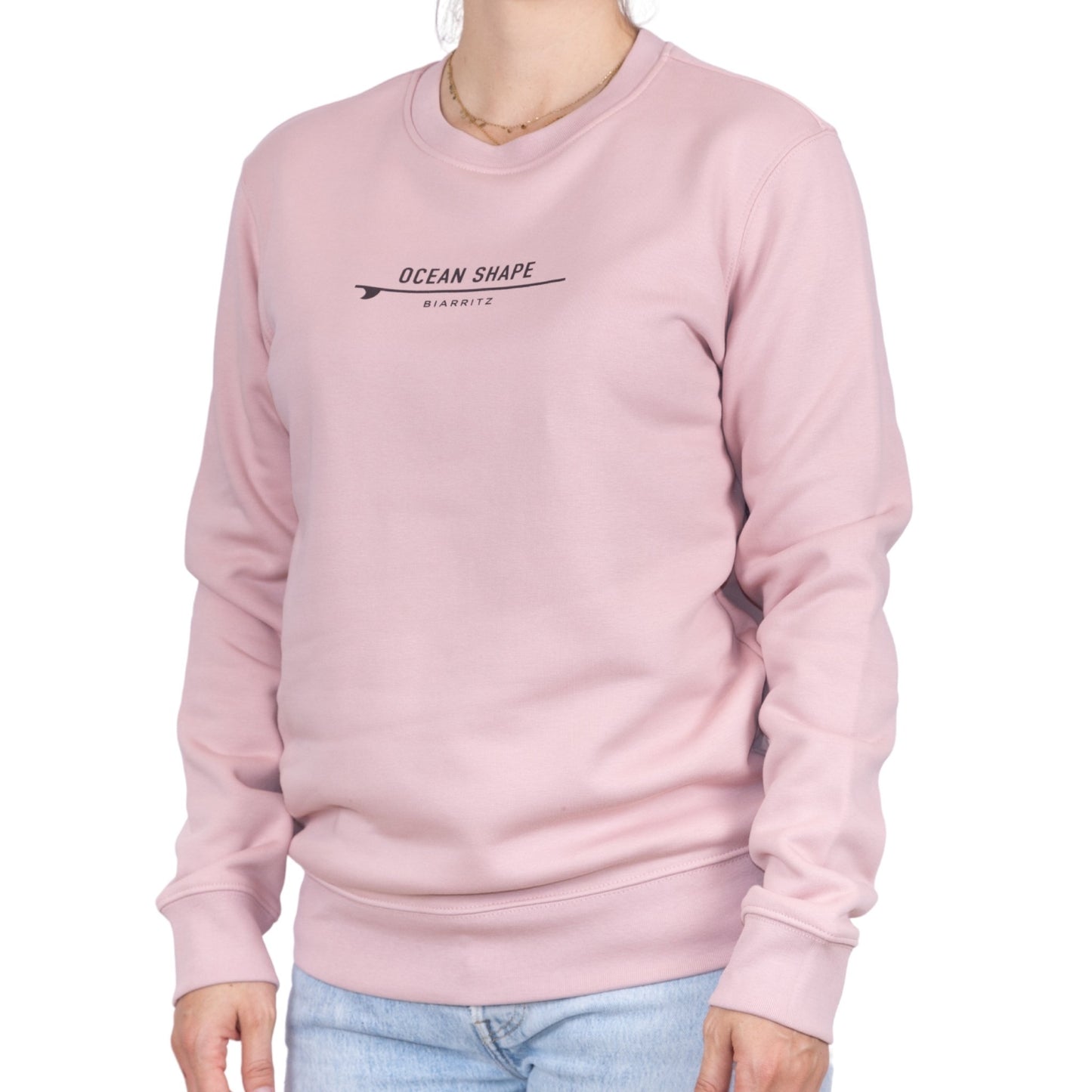 Sweat unisexe rose pale en coton biologique avec petite signature "ocean shape Biarritz" sur surf marron foncé sur la poitrine, vu de face sur mannequin femme.