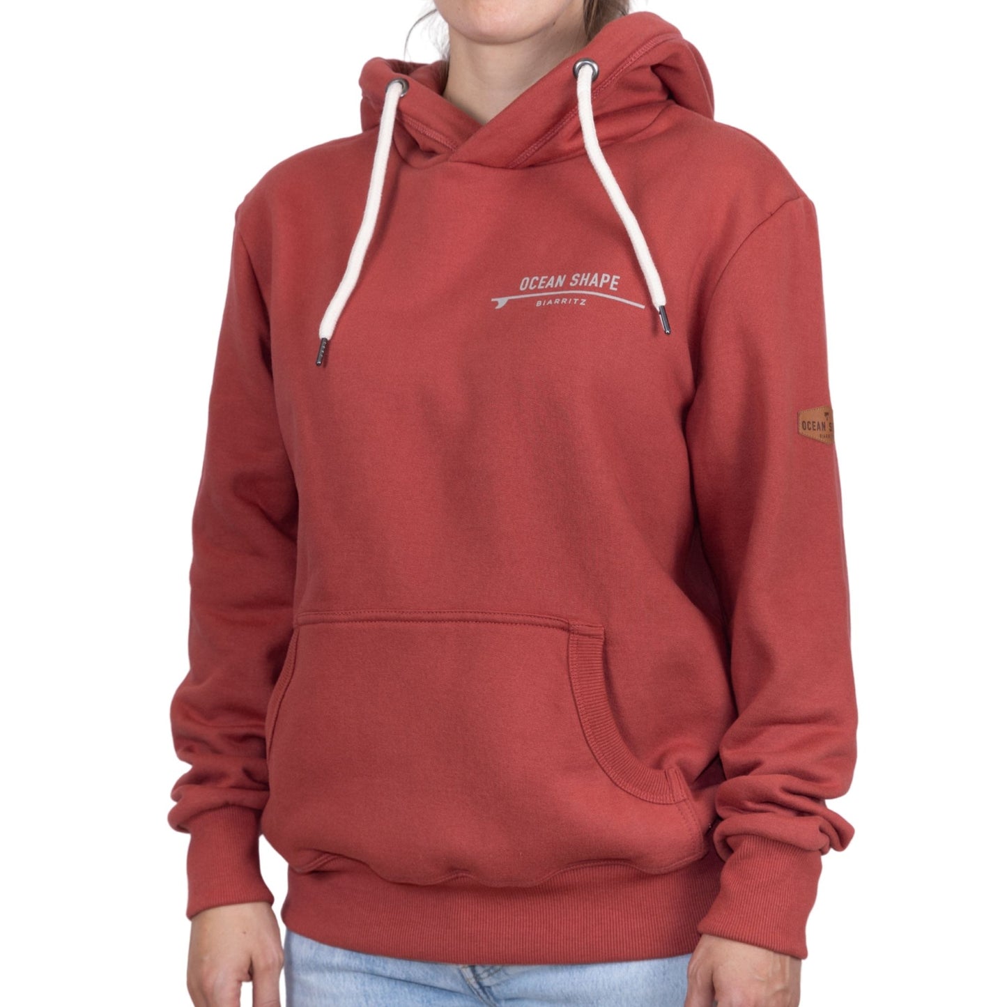 Sweat unisexe à capuche terracotta avec signature "Ocean Shape Biarritz" beige sur la poitrine, vu de face sur mannequin femme