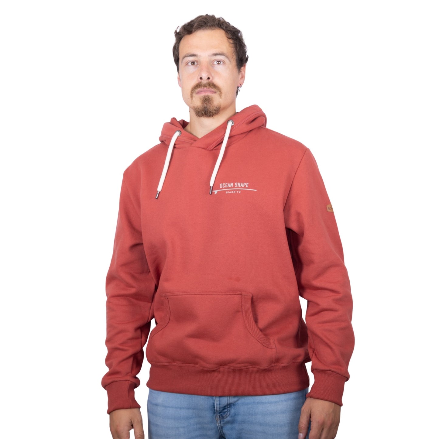 Sweat unisexe à capuche terracotta avec signature "Ocean Shape Biarritz" beige sur la poitrine, vu de face sur mannequin homme