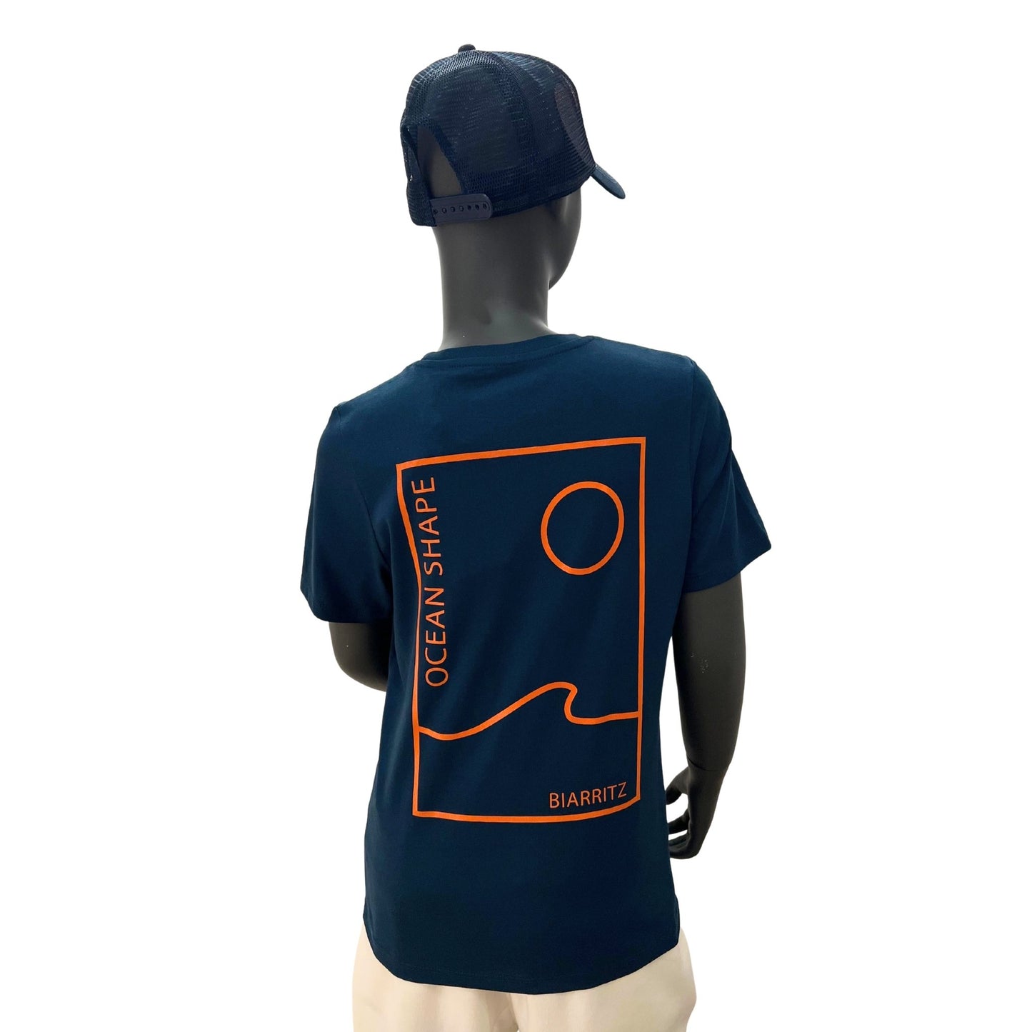t shirt à manches courtes enfant unisexe couleur peacock bleu, en coton biologique, sur un mannequin enfant de face.
Derrière : grand dessin minimaliste d'une vague et d'un soleil avec écriture "as free as the ocean" orange fluo.