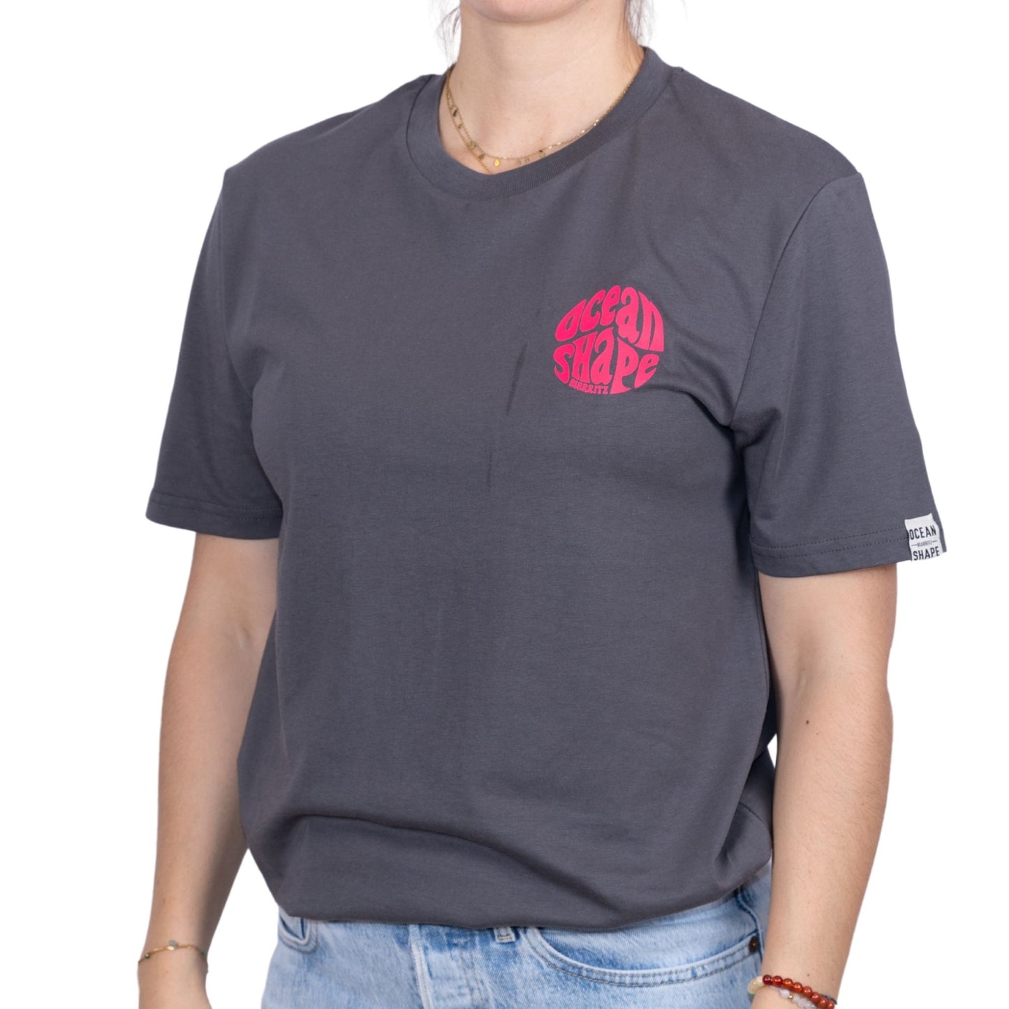 Tee-shirt gris foncé en coton biologique avec petit logo bubble ocean shape Biarritz rose fluo sur la poitrine, vu de face sur mannequin femme