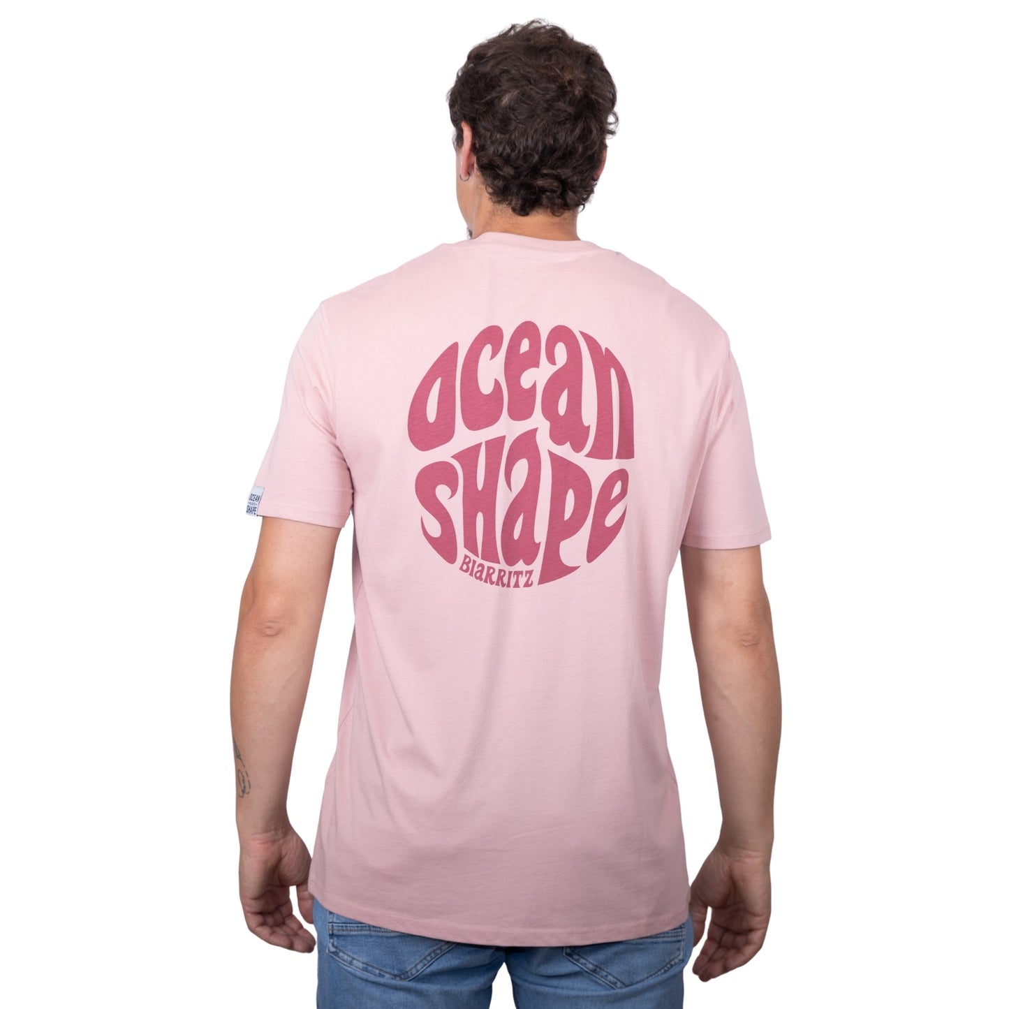 Tee-shirt unisexe rose pale en coton biologique avec gros logo ocean shape Biarritz bubble rose foncé en haut du dos, vu de dos sur mannequin homme