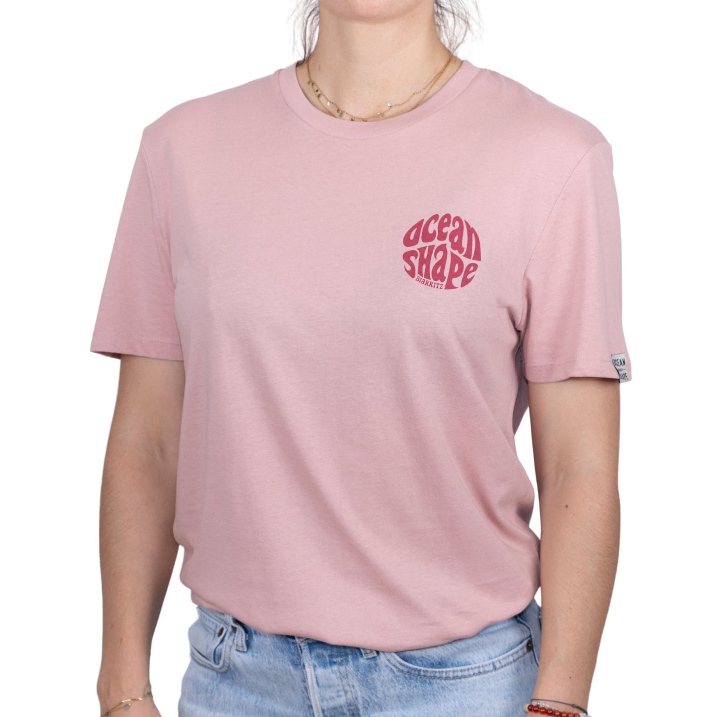 Tee-shirt unisexe rose pale en coton biologique avec petit logo ocean shape Biarritz bubble rose foncé sur la poitrine, vu de face sur mannequin femme