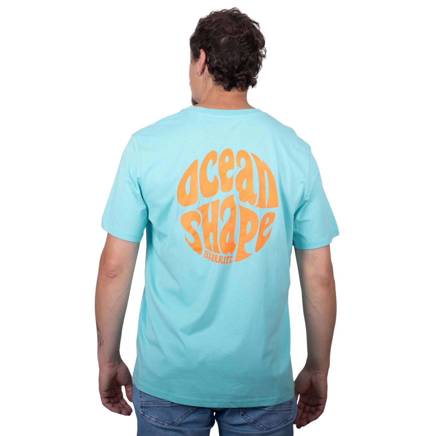 Tee-shirt unisexe bleu ciel en coton biologique avec gros logo ocean shape Biarritz bubble orange fluo en haut du dos, vu de dos sur mannequin homme