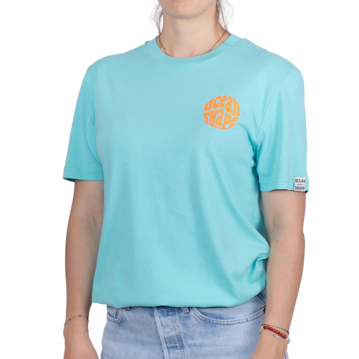 Tee-shirt unisexe bleu ciel en coton biologique avec petit logo ocean shape Biarritz bubble orange fluo sur la poitrine, vu de face sur mannequin femme
