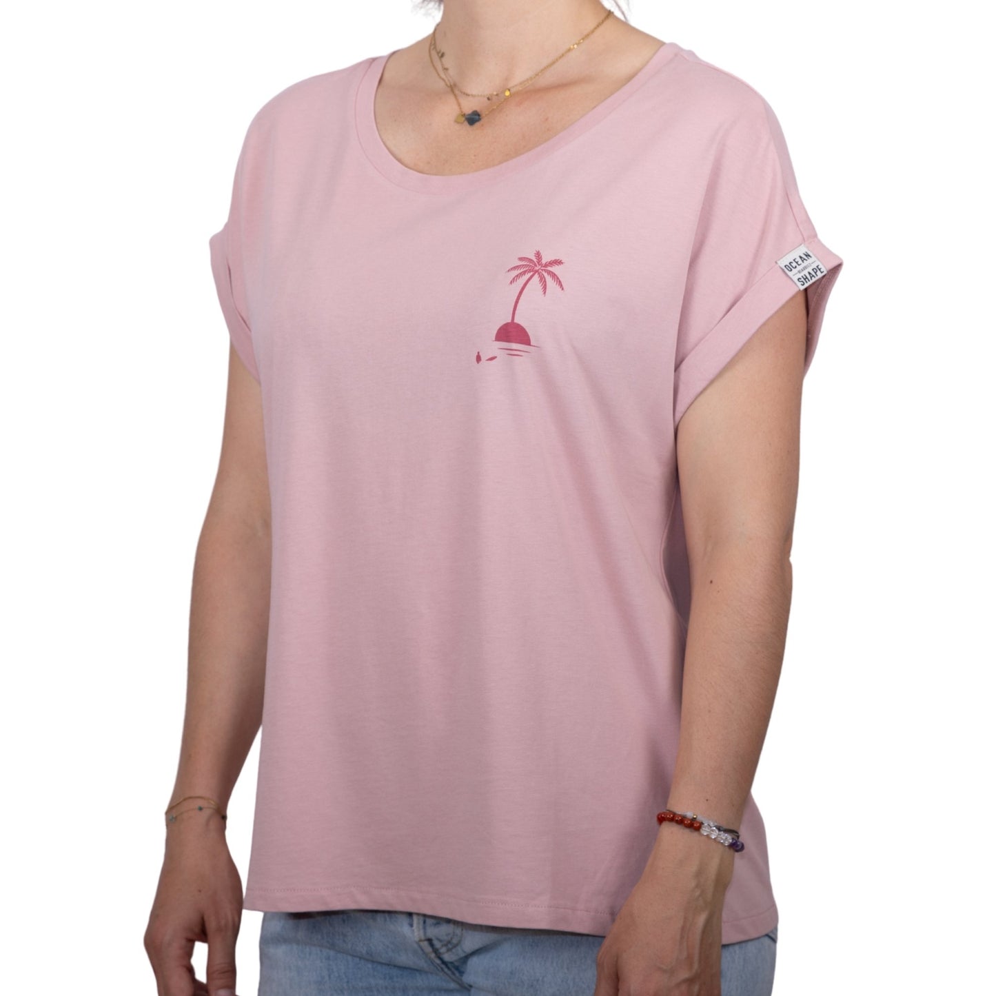 Tee-shirt femme en coton biologique rose pale avec petit dessin palmier sur île couleur framboise sur la poitrine, vu de face sur mannequin femme