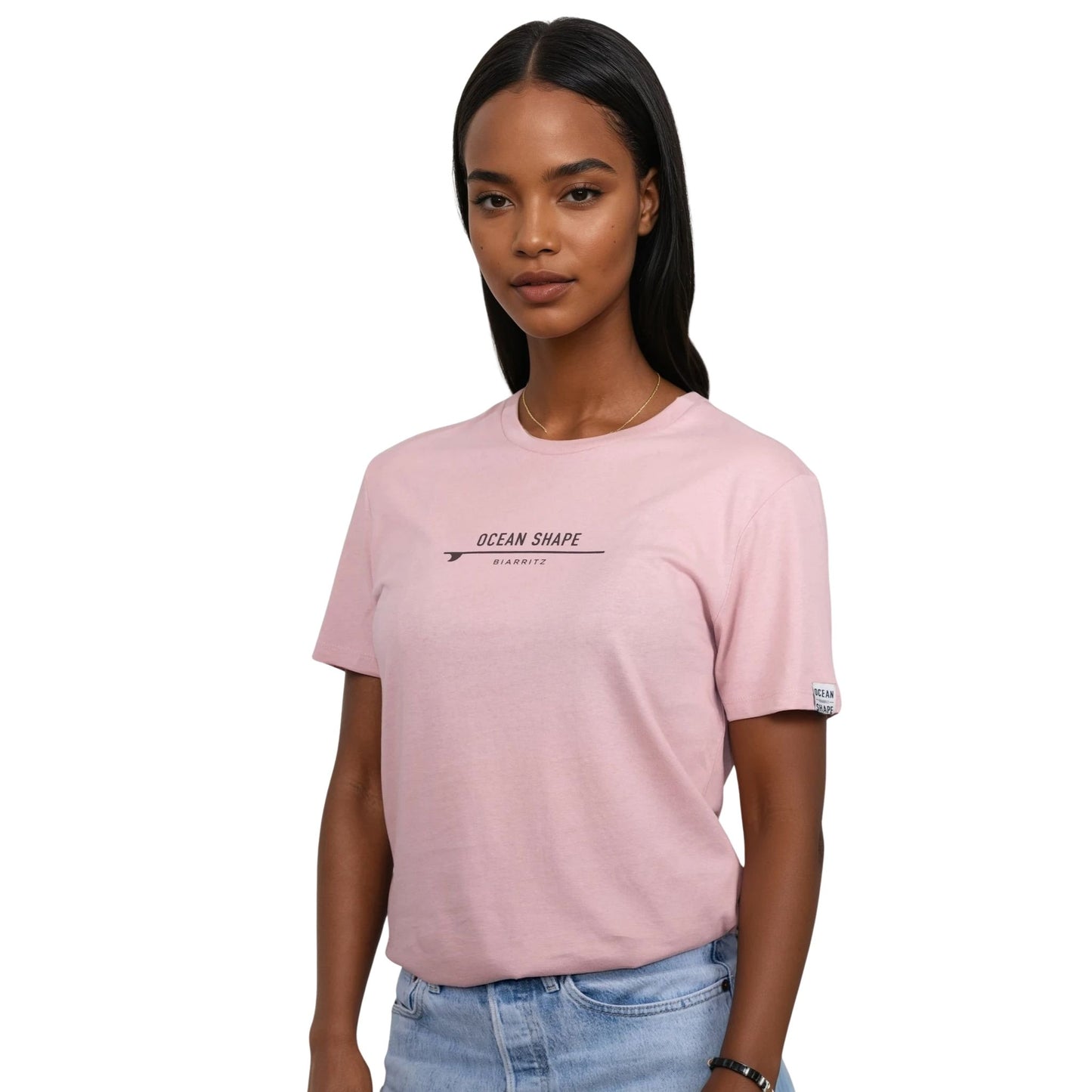 Tee-shirt unisexe rose pale en coton biologique avec petite signature "ocean shape Biarritz" sur surf marron foncé sur la poitrine, vu de face sur mannequin femme