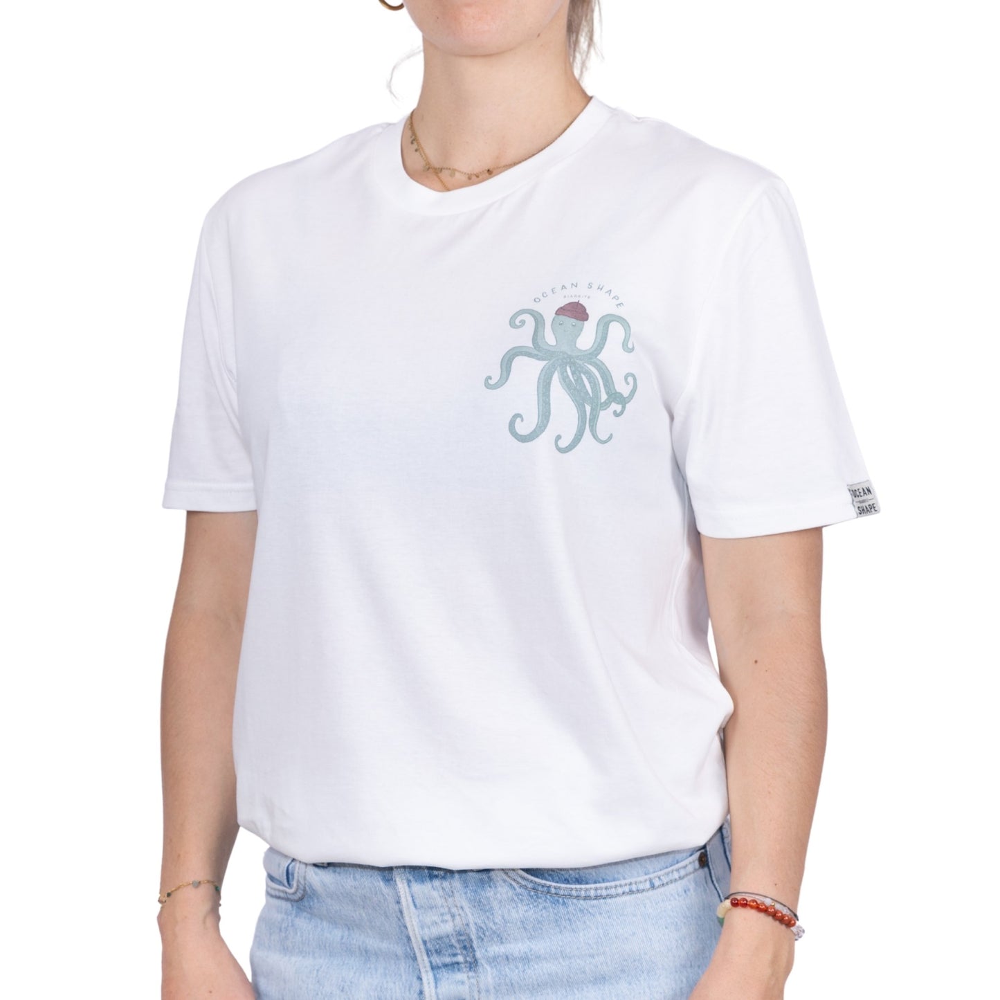 T-shirt unisexe blanc en coton biologique avec petit dessin de poulpe vert avec berret marron et écriture "Ocean Shape Biarritz" sur la poitrine, vue de face sur mannequin femme