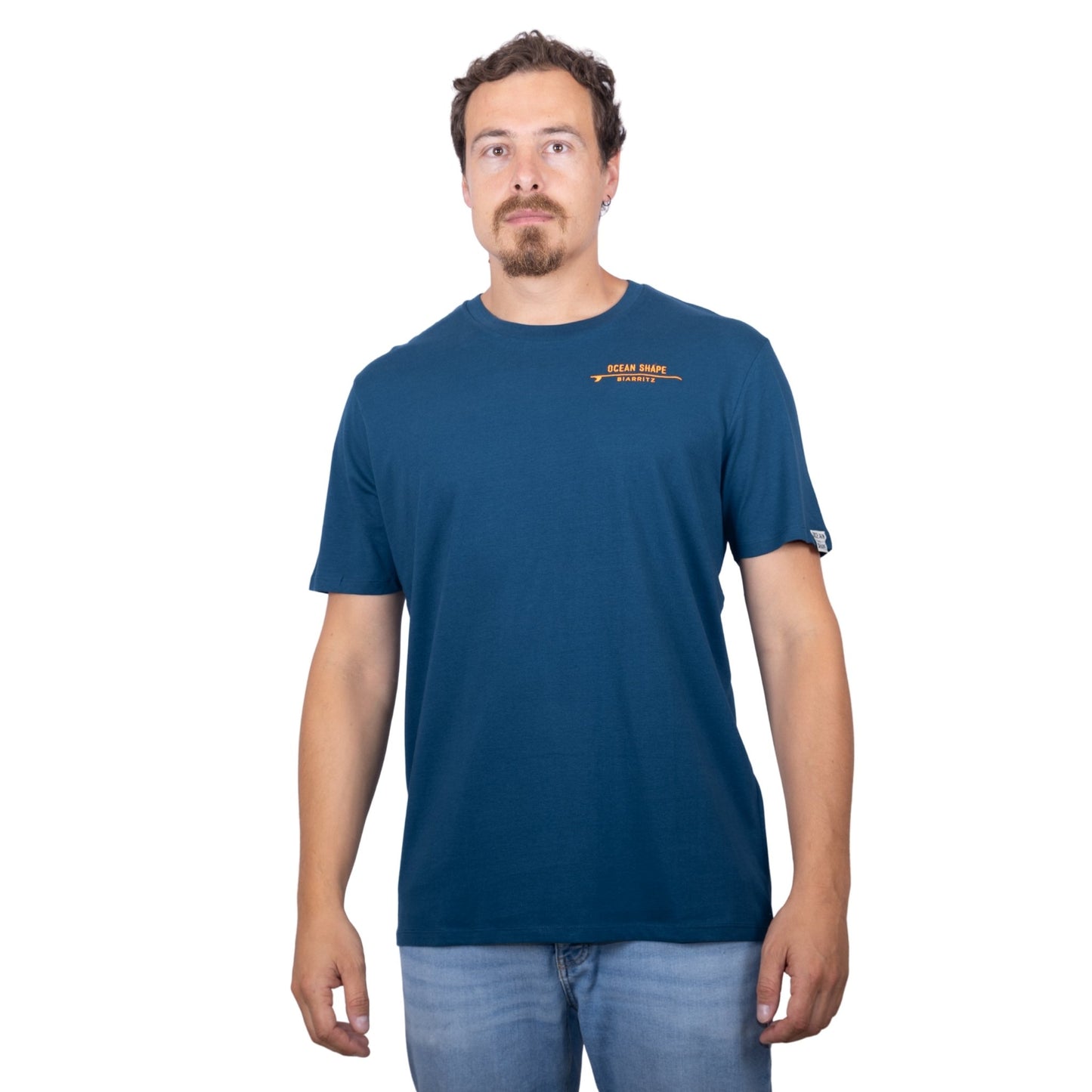 T-shirt unisexe bleu pétrole en coton biologique avec logo signature « ocean shape Biarritz » sur planche de surf minimaliste orange fluo, vue de face sur mannequin homme