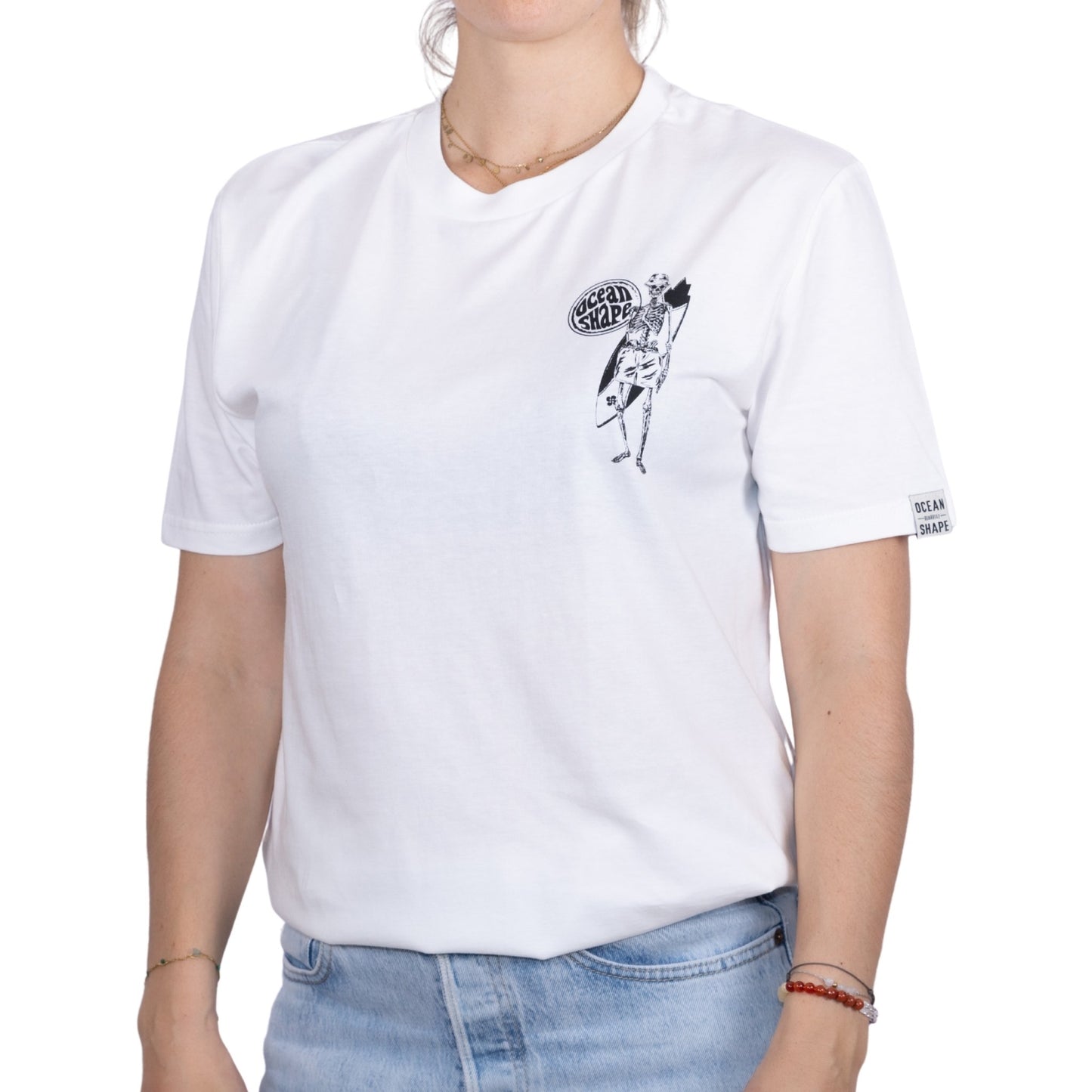T-shirt unisexe en coton biologique blanc avec petit dessin noir de squelette surfeur sur la poitrine, vu de face sur mannequin femme