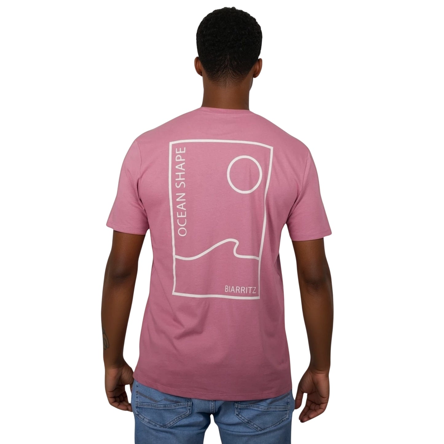 Tee-shirt unisexe rose foncé en coton biologique avec grand dessin vague / soleil minimaliste et écriture "ocean shape Biarritz" beige dans le dos, vu de dos sur mannequin homme.