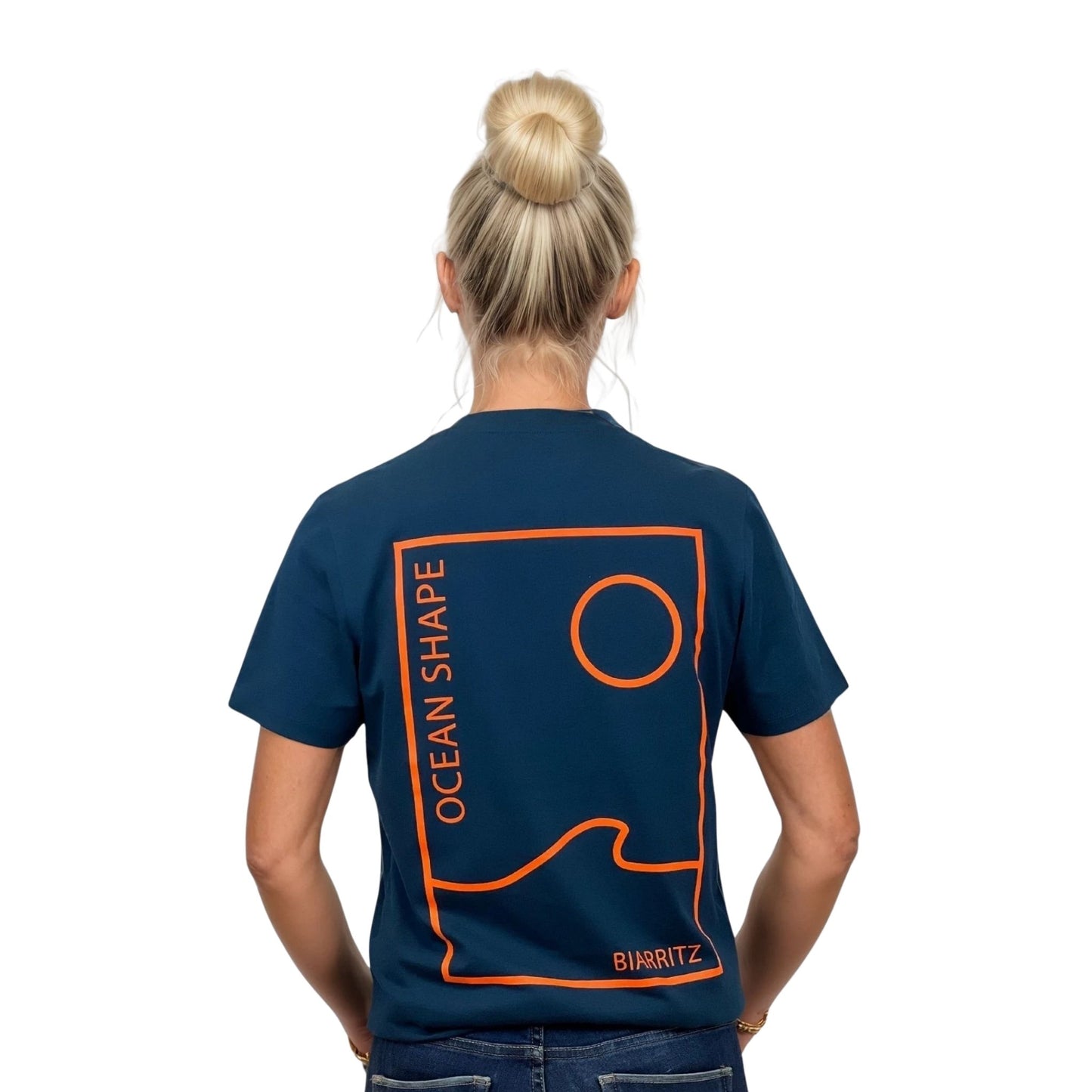 Tee-shirt unisexe bleu petrole en coton biologique avec grand encadré vague / soleil minimaliste + écriture "ocean shape Biarritz" orange fluo dans le dos, vu de dos sur mannequin femme.
