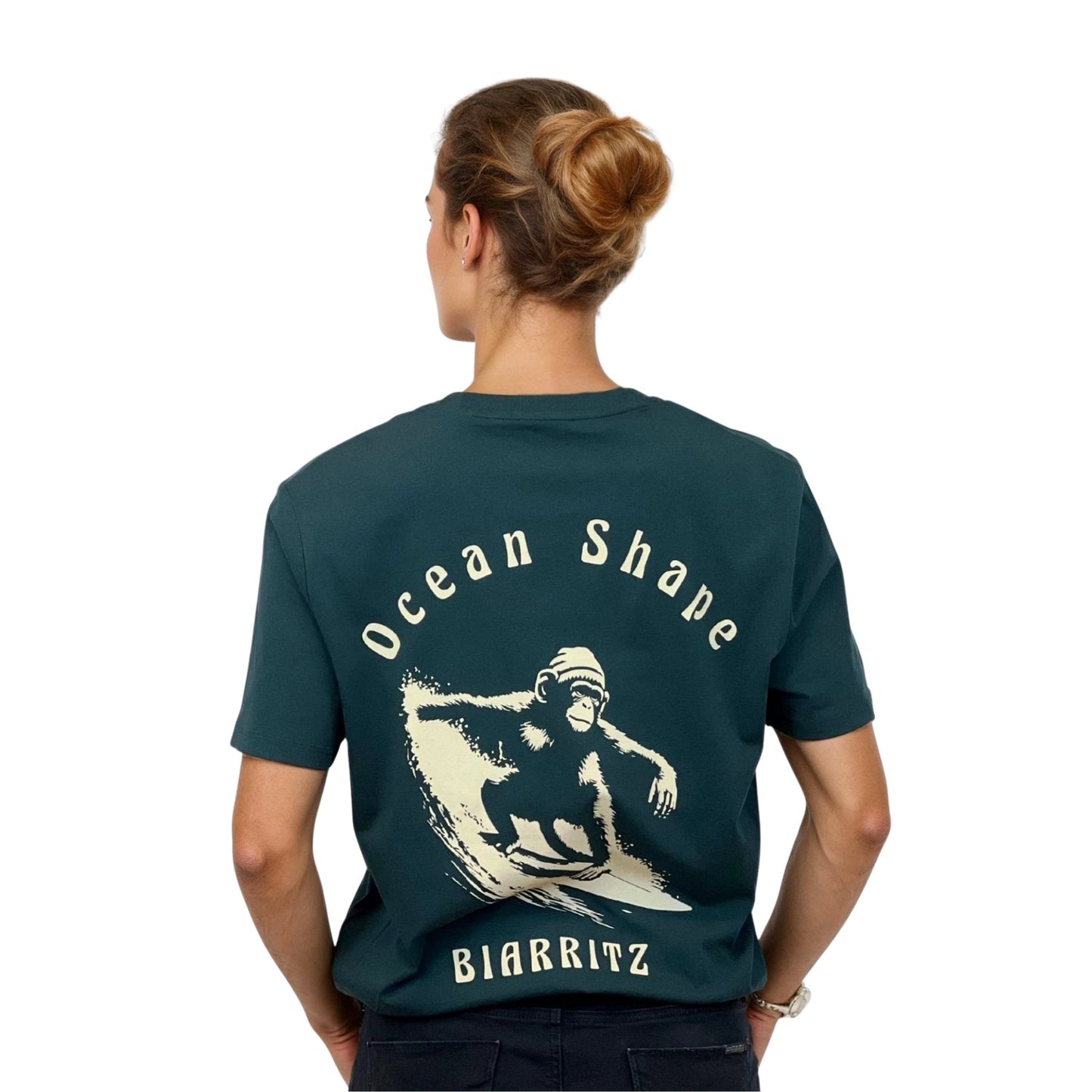 Tee-shirt unisexe vert foncé en coton biologique avec gros dessin de singe qui surfe et écriture « ocean shape Biarritz » beige dans le dos, vu de dos sur mannequin femme.