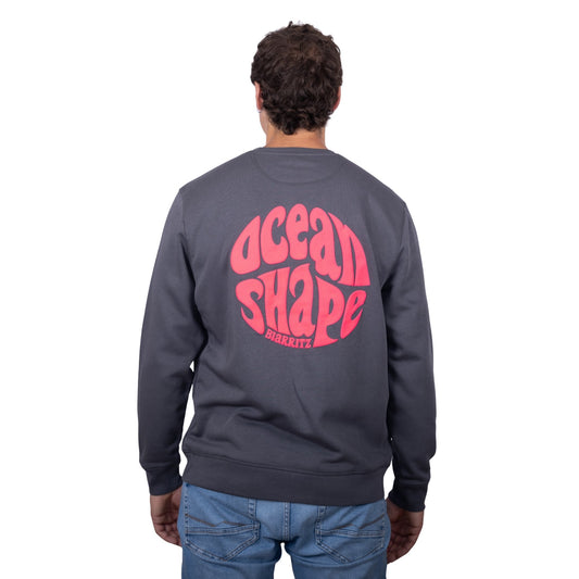 Sweat unisexe sans capuche gris anthracite avec gros logo bubble "ocean shape biarritz" rose fluo dans le dos, vu de dos sur mannequin homme