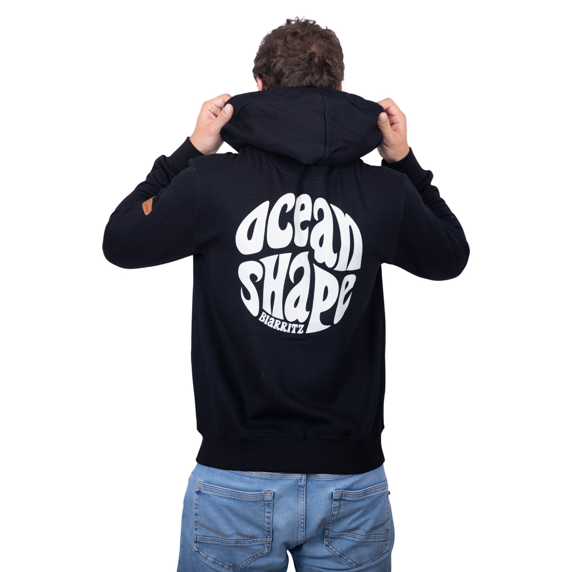 Sweat unisexe à capuche noir avec gros logo bubble "Ocean Shape Biarritz" blanc dans le dos, vu de dos sur mannequin homme