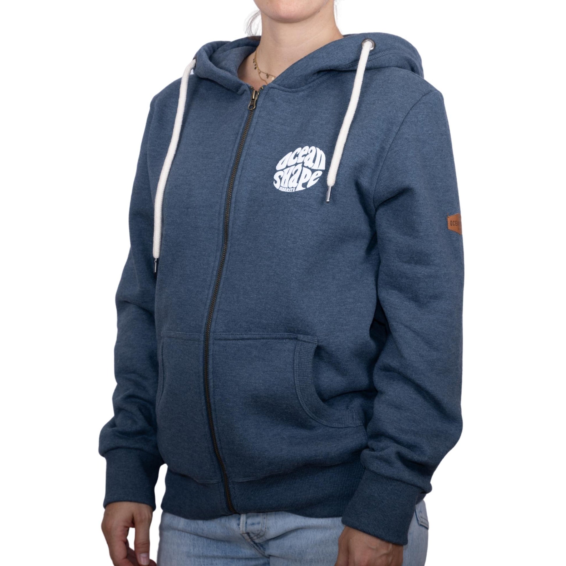 Sweat unisexe zippé à capuche bleu ocean avec petit logo bubble "Ocean Shape Biarritz" blanc sur la poitrine, vu de face sur mannequin femme