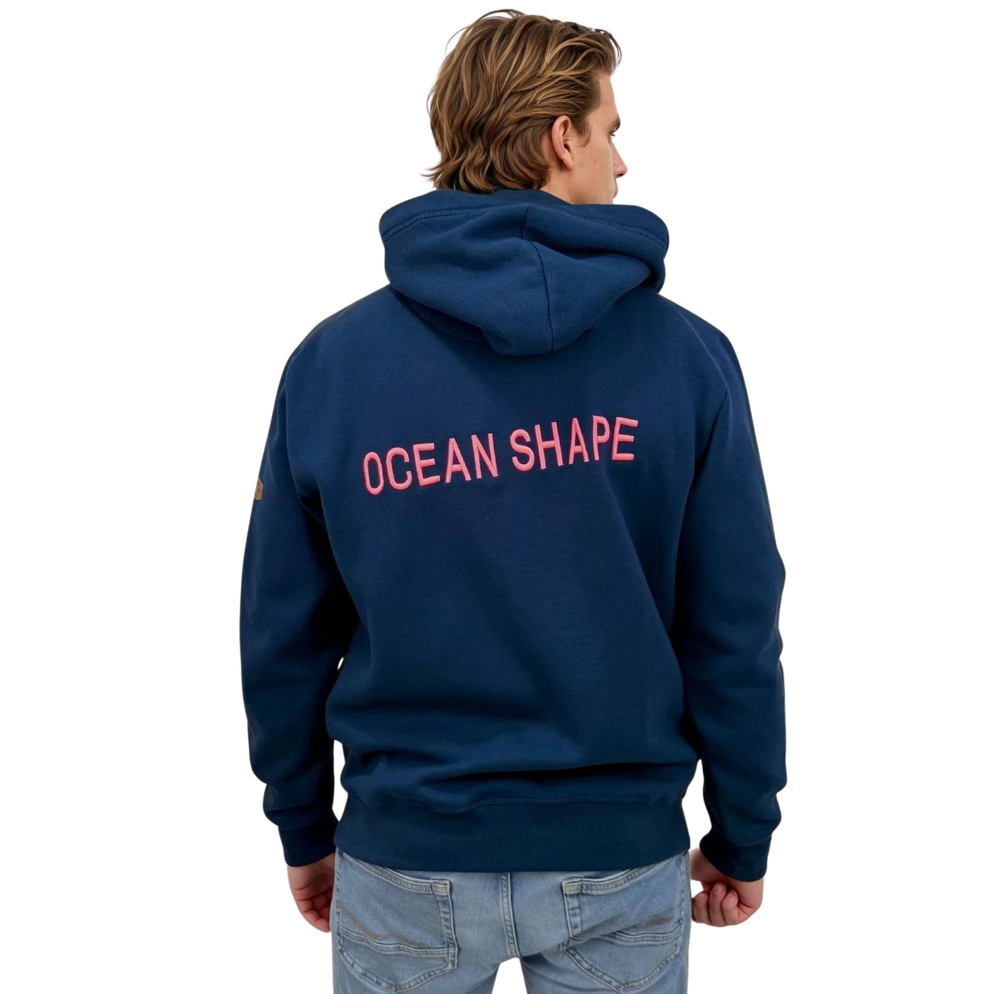 Sweat à capuche unisexe OceanShape couleur bleu paon, porté par un homme de dos.
Inscription "OceanShape" avec la mention "Biarritz" brodé en rose, et en majuscule.
Style casual et surf, inspiré de la côte basque.