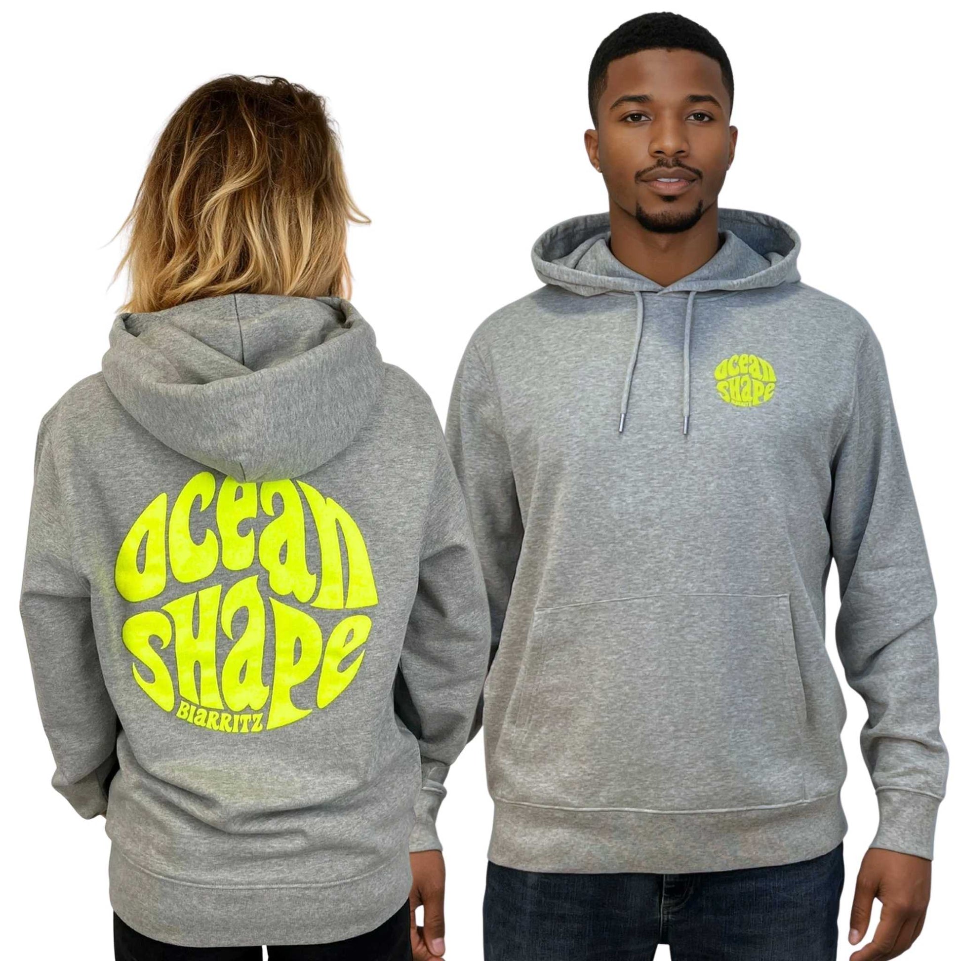Sweat à capuche unisexe gris.
Petit logo bubble "Ocean Shape Biarritz" en encre gonflante jaune fluo sur la poitrine gauche et gros logo bubble "Ocean Shape Biarritz" en encre gonflante jaune fluo dans le dos.
Vu de face sur mannequin homme et de dos sur mannequin femme.