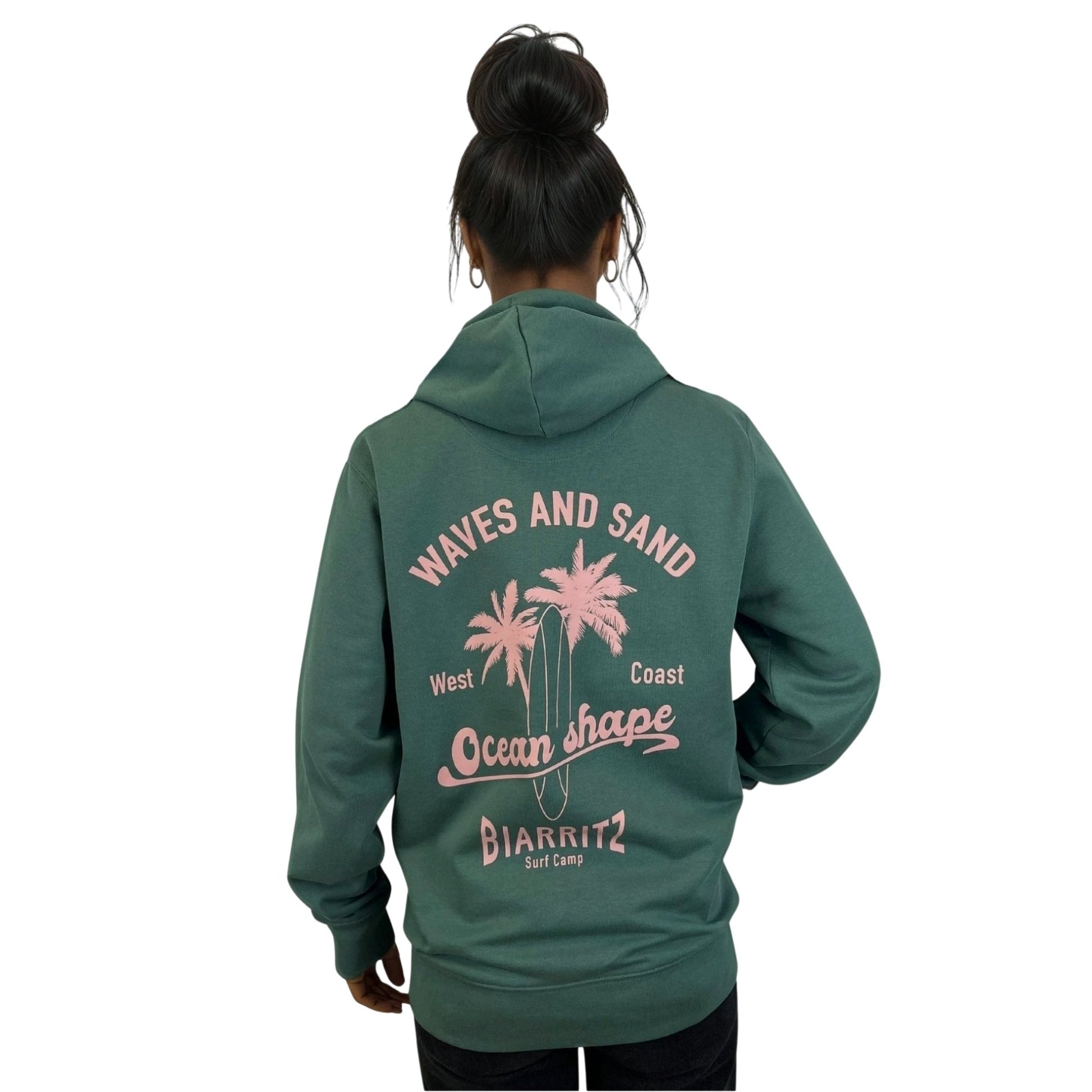 Sweat à capuche zippé OceanShape  unisexe glazed green.
Vu de dos sur mannequin femme.
Dos : écriture "waves and sand, west coast, Ocean Shape Biarritz, surf camp"
Style casual et surf inspiré de la côte basque.