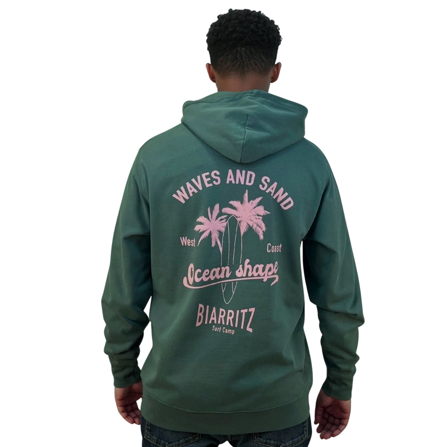 Sweat à capuche zippé OceanShape  unisexe glazed green.
Vu de dos sur mannequin homme.
Dos : écriture "waves and sand, west coast, Ocean Shape Biarritz, surf camp" en rose
Style casual et surf inspiré de la côte basque.