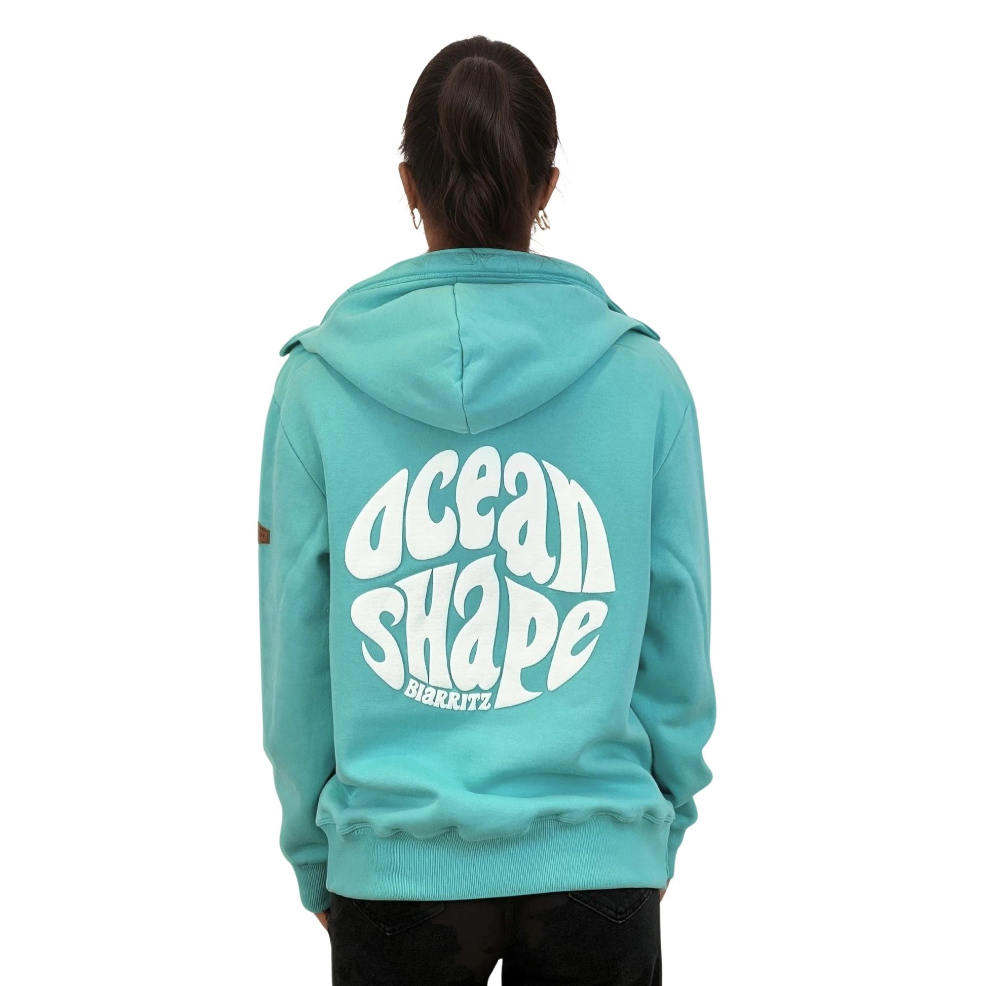 Sweat à capuche unisexe turquoise.
Gros logo bubble "Ocean Shape Biarritz" en encre gonflante blanche dans le dos.
Vu de dos sur mannequin femme.