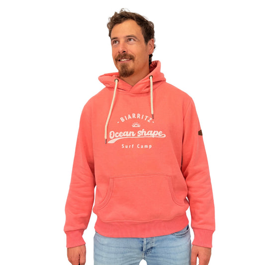 sweat à capuche ocean shape en coton biologique corail avec écriture "biarritz, ocean shape, surf camp" en encre gonflante blanche sur la poitrine, vu de face sur mannequin homme