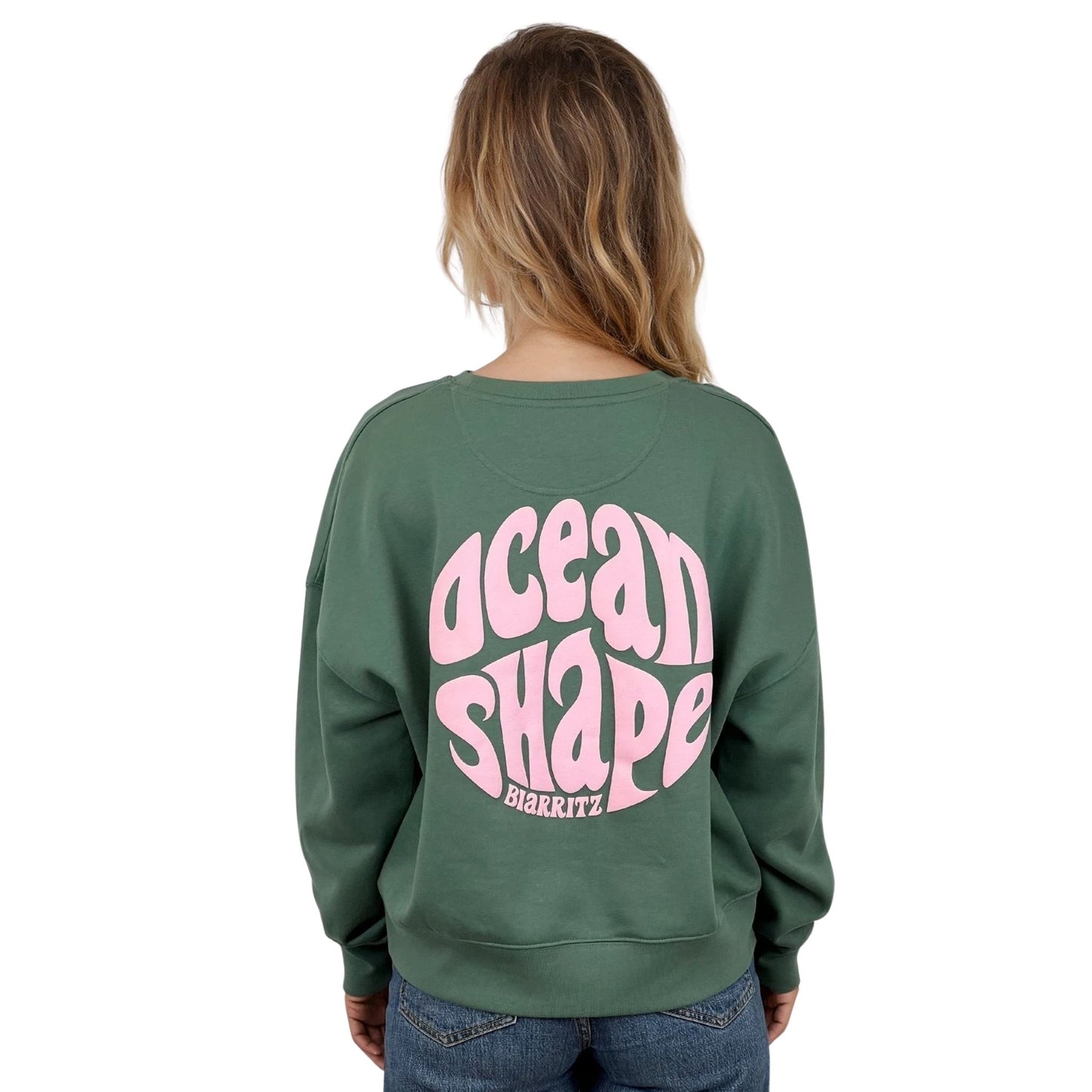 Sweat femme court et oversize, col rond, épaules tombantes, 100 % coton biologique, couleur vert sauge.
Gros logo bubble "Ocean shape Biarritz" rose pâle dans le dos.
Vu de dos sur mannequin femme.