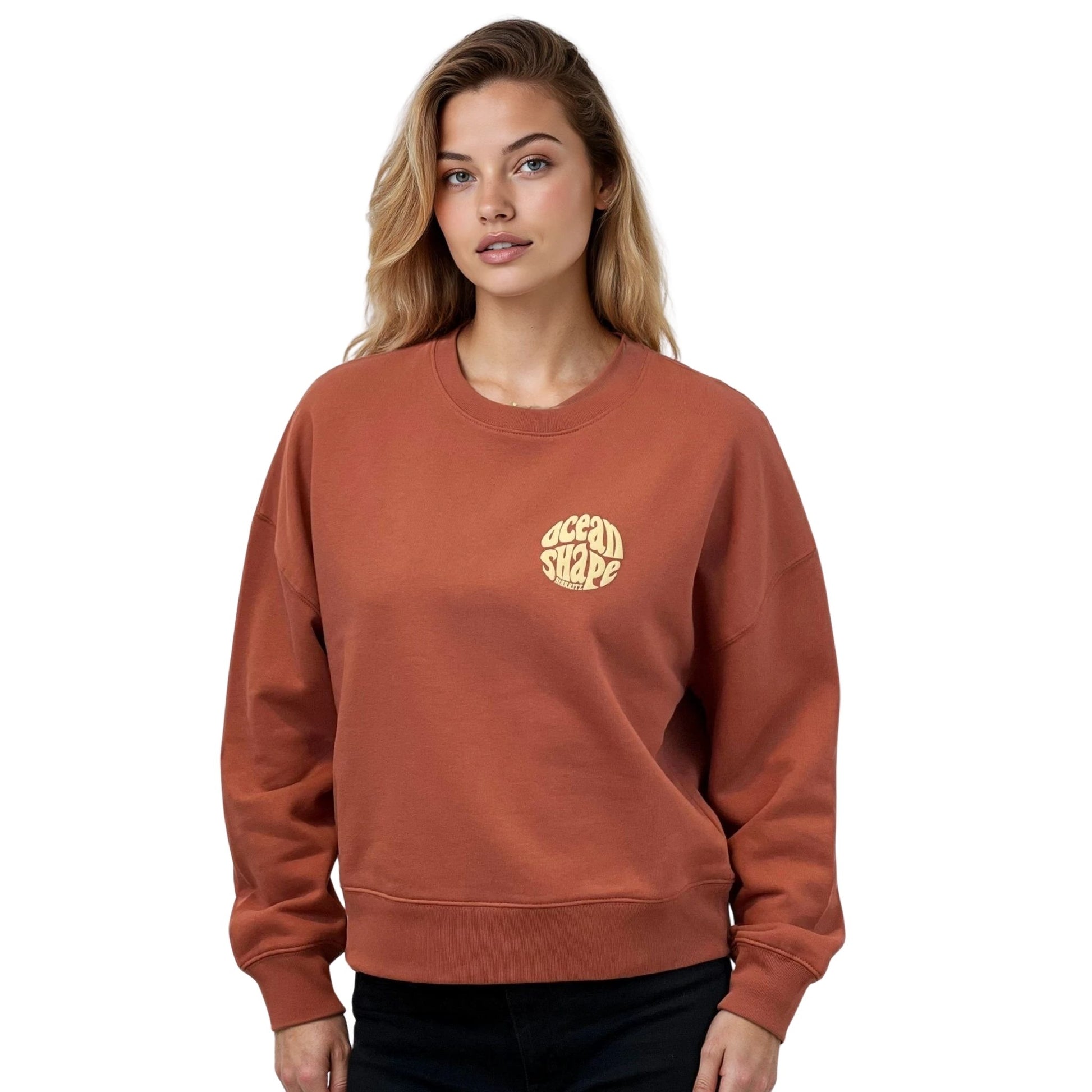 Sweat femme court et oversize, col rond, épaules tombantes, 100 % coton biologique, couleur terracotta.
Petit logo bubble "Ocean shape Biarritz" beige sur la poitrine gauche.
Vu de face sur mannequin femme.