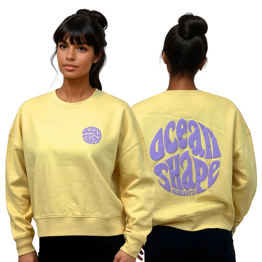 Sweat femme court et oversize, col rond, épaules tombantes, 100 % coton biologique, jaune.
Devant : petit logo bubble "Ocean shape Biarritz" violet sur la poitrine gauche.
Dos : gros logo bubble "Ocean shape Biarritz" violet.
Vu de face et de dos sur mannequin femme.