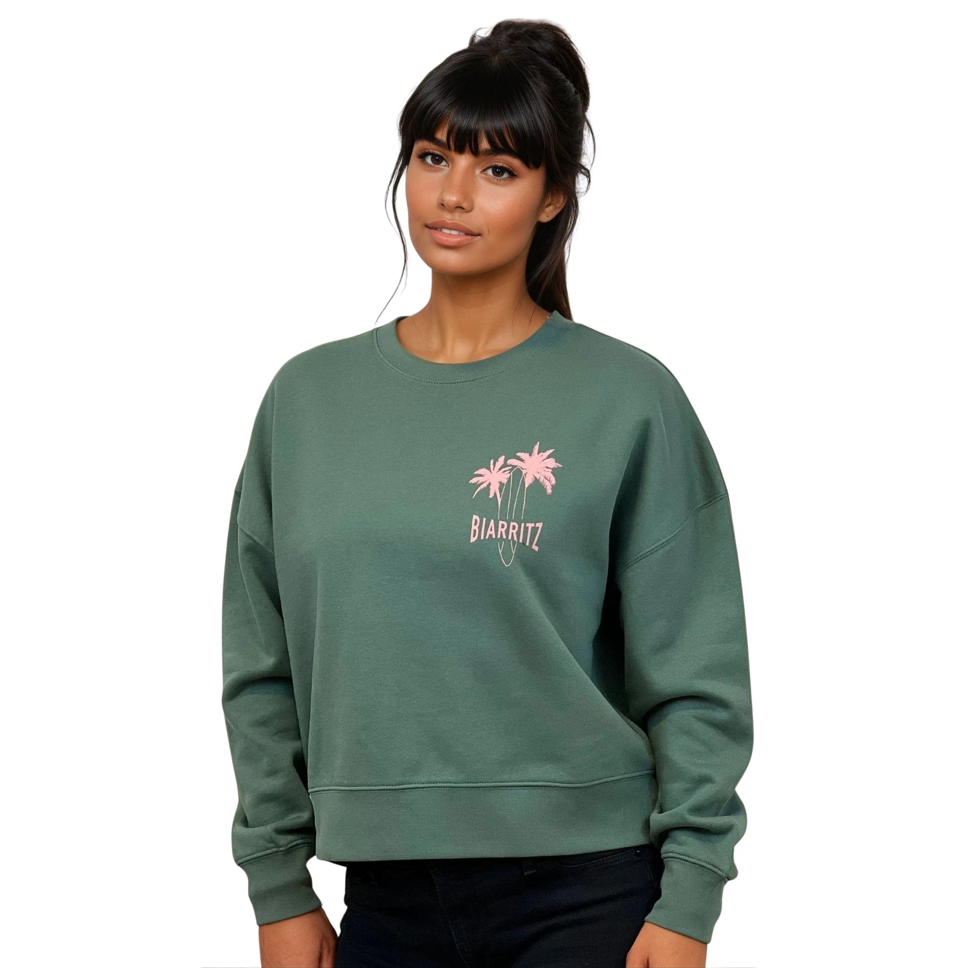 Sweat femme court et oversize, col rond, épaules tombantes, 100 % coton biologique, couleur vert sauge.
Petit dessin rose pâle de planche de surf et palmiers + écriture "Biarritz" sur la poitrine gauche.
Vu de face sur mannequin femme.