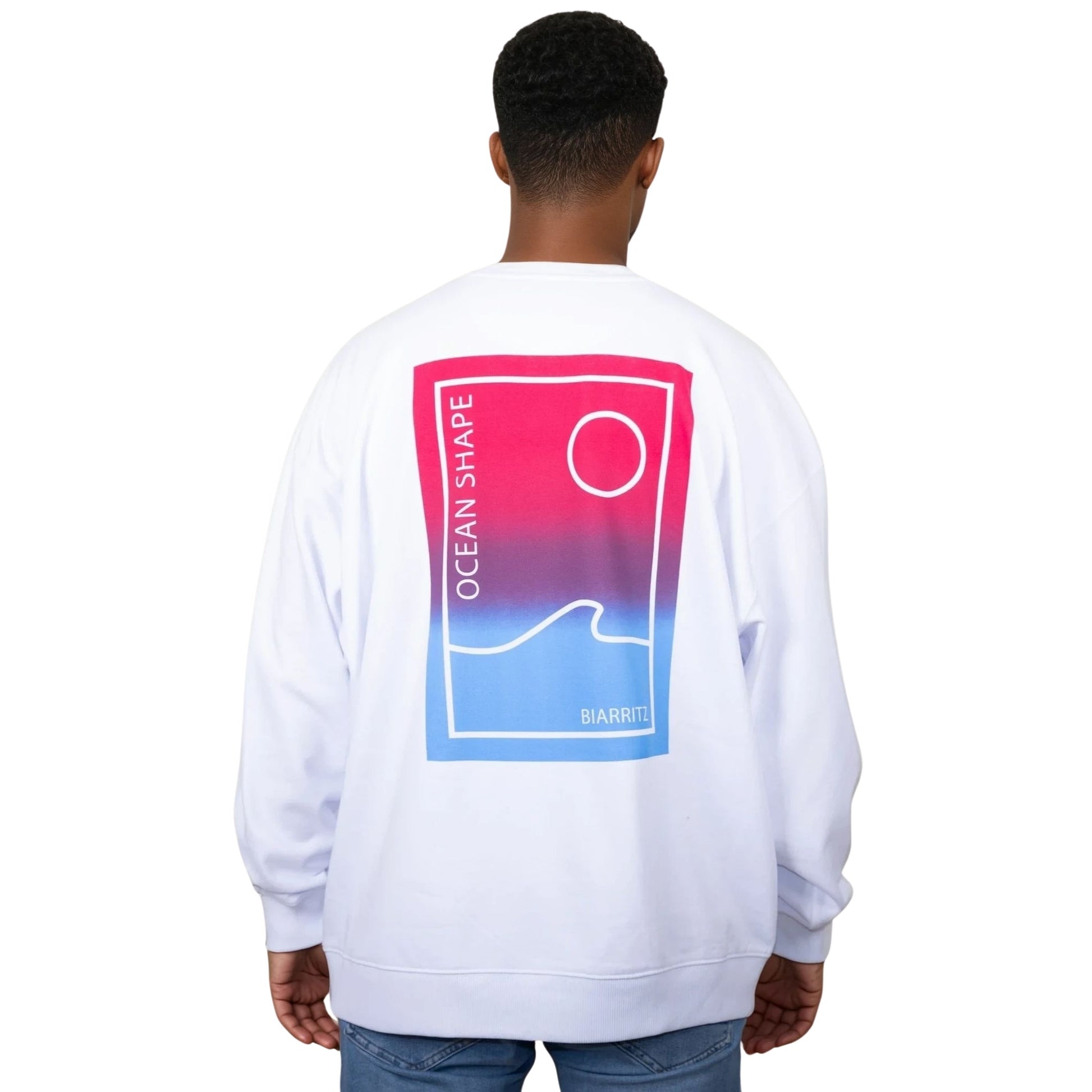Sweat unisexe blanc en coton biologique avec grand encadré vague  / soleil minimaliste dégradé rose et bleu + écriture "ocean shape Biarritz" dans le dos, vu de dos sur mannequin homme