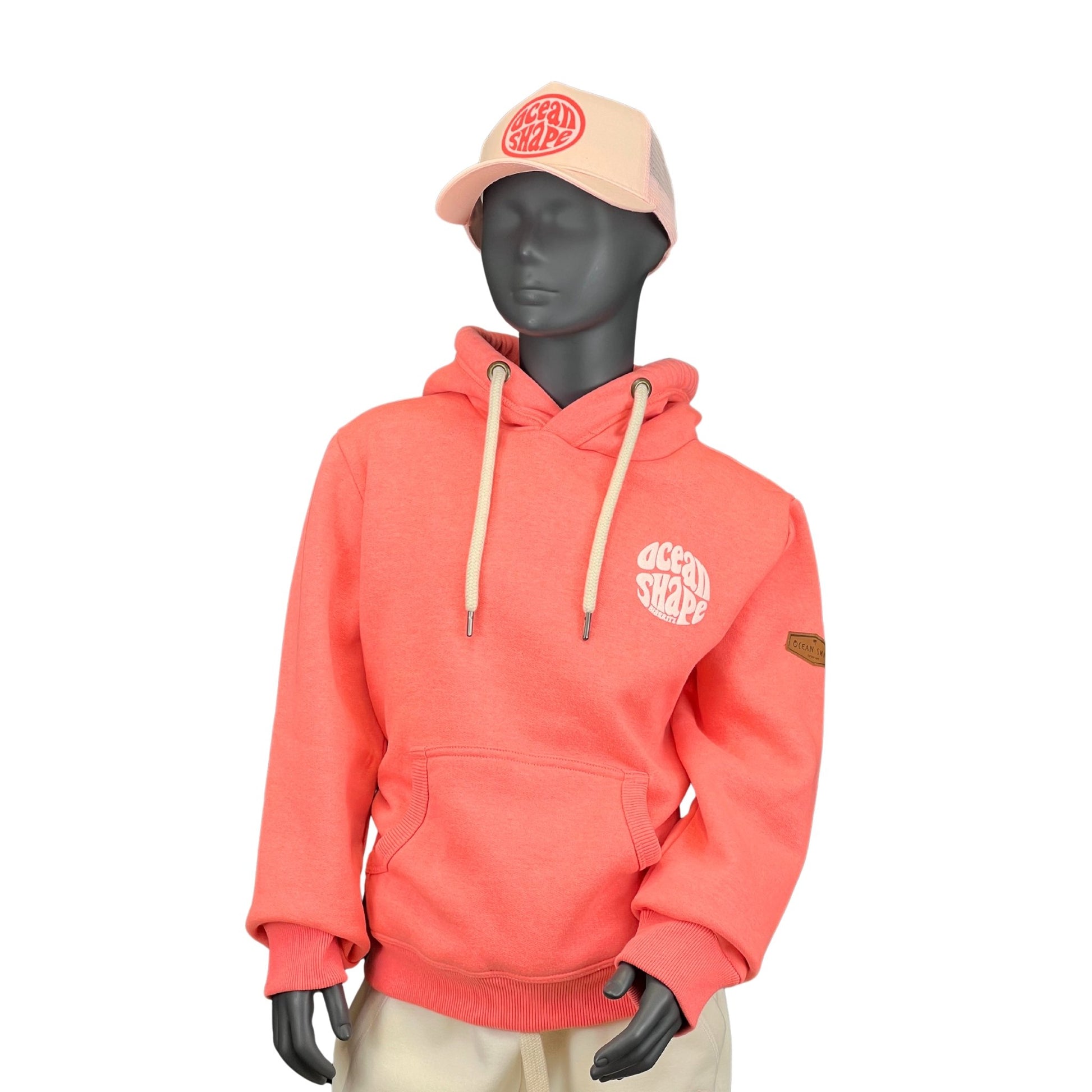 sweat à capuche unisexe enfant, en coton biologique ocean shape de couleur corail sur un mannequin enfant de face 
Devant : poche kangourou, et logo bubble ocean shape blanc en relief avec écrit biarritz