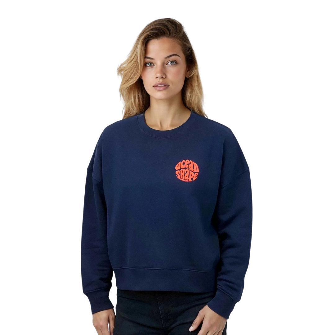 Sweat femme court et oversize, col rond, épaules tombantes, 100 % coton biologique, bleu marine.
Petit logo bubble "Ocean shape Biarritz" corail fluo sur la poitrine gauche.
Vu de face sur mannequin femme.