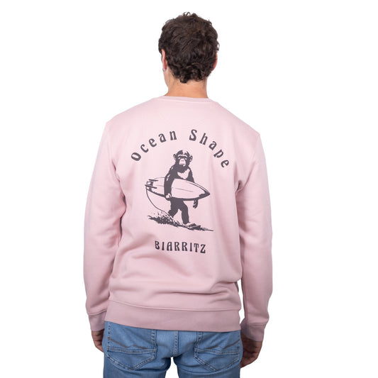 Sweat unisexe rose pale en coton biologique avec gros dessin de singe surfeur et écriture « ocean shape Biarritz » marron foncé dans le dos, vu de dos sur mannequin homme 