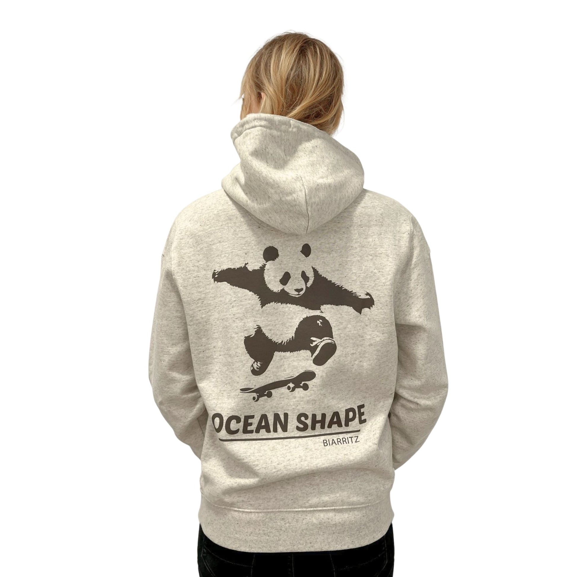 Sweat à capuche unisexe beige chiné.
Vu de dos sur mannequin femme. Logo du panda faisant du skate et "ocean shape Biarritz" de couleur marron en dessous.