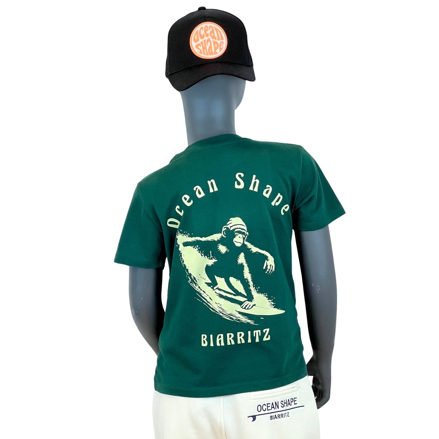 tshirt enfant ocean shape vert foncé, 100% coton biologique.
Illustration beige d'un singe qui fait du surf et écritures "ocean shape, biarritz".
Vu de dos sur mannequin enfant.