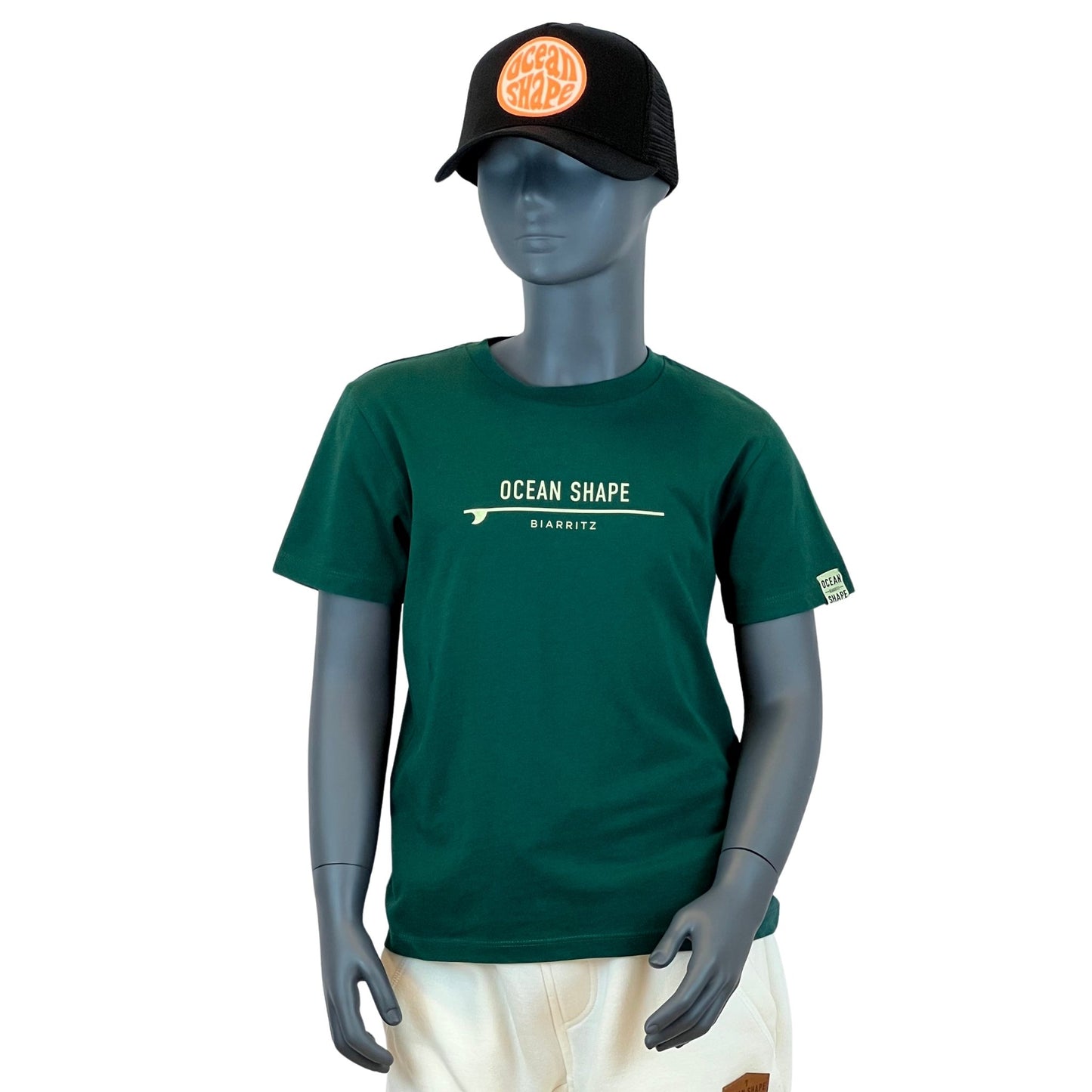tshirt enfant ocean shape vert foncé, 100% coton biologique.
Ecriture "ocean shape biarritz" beige avec une planche de surf fine au milieu.
Vu de face sur mannequin enfant.