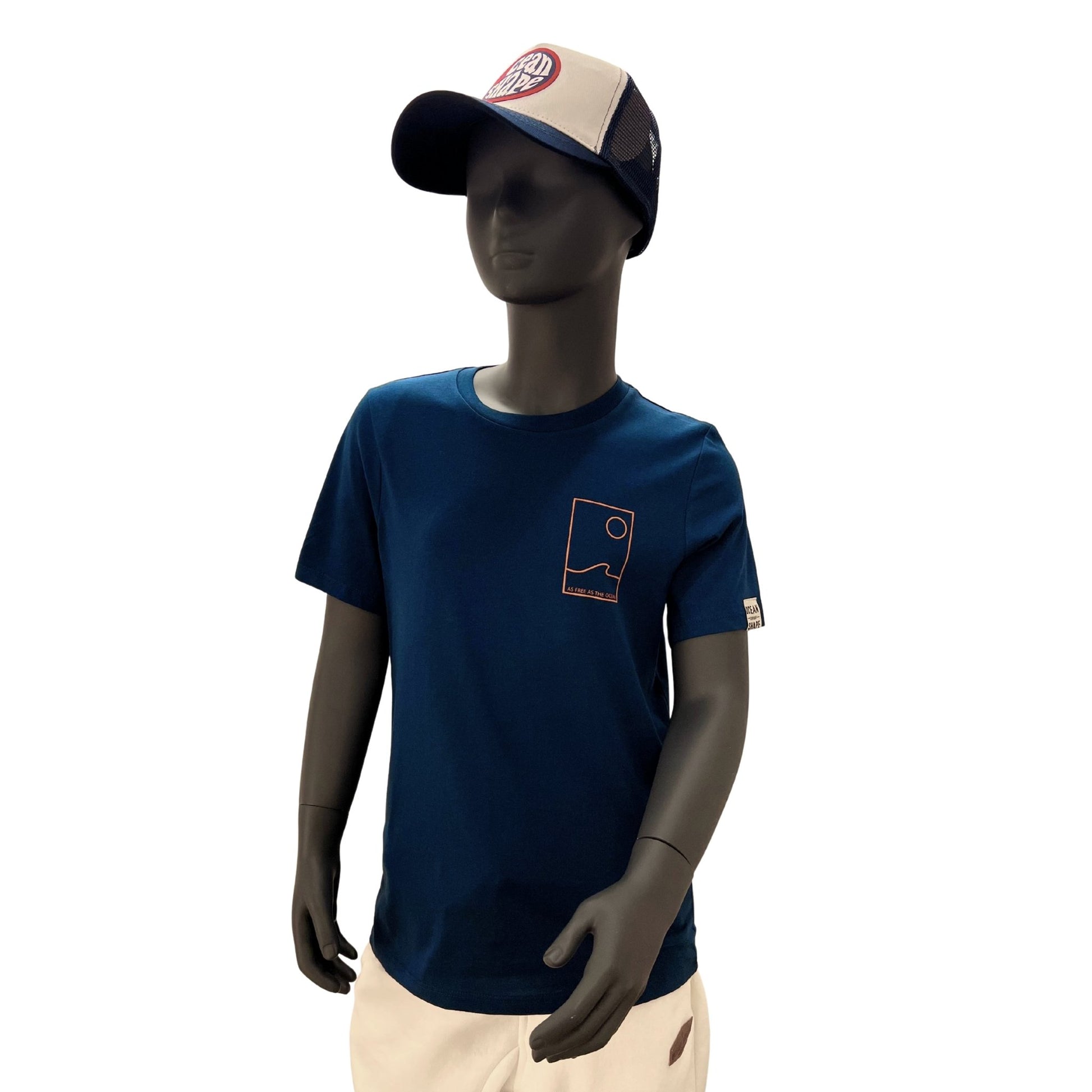 t shirt à manches courtes enfant unisexe couleur peacock bleu, en coton biologique, sur un mannequin enfant de face.
Devant : dessin minimaliste d'une vague et d'un soleil avec écriture "as free as the ocean" orange fluo.