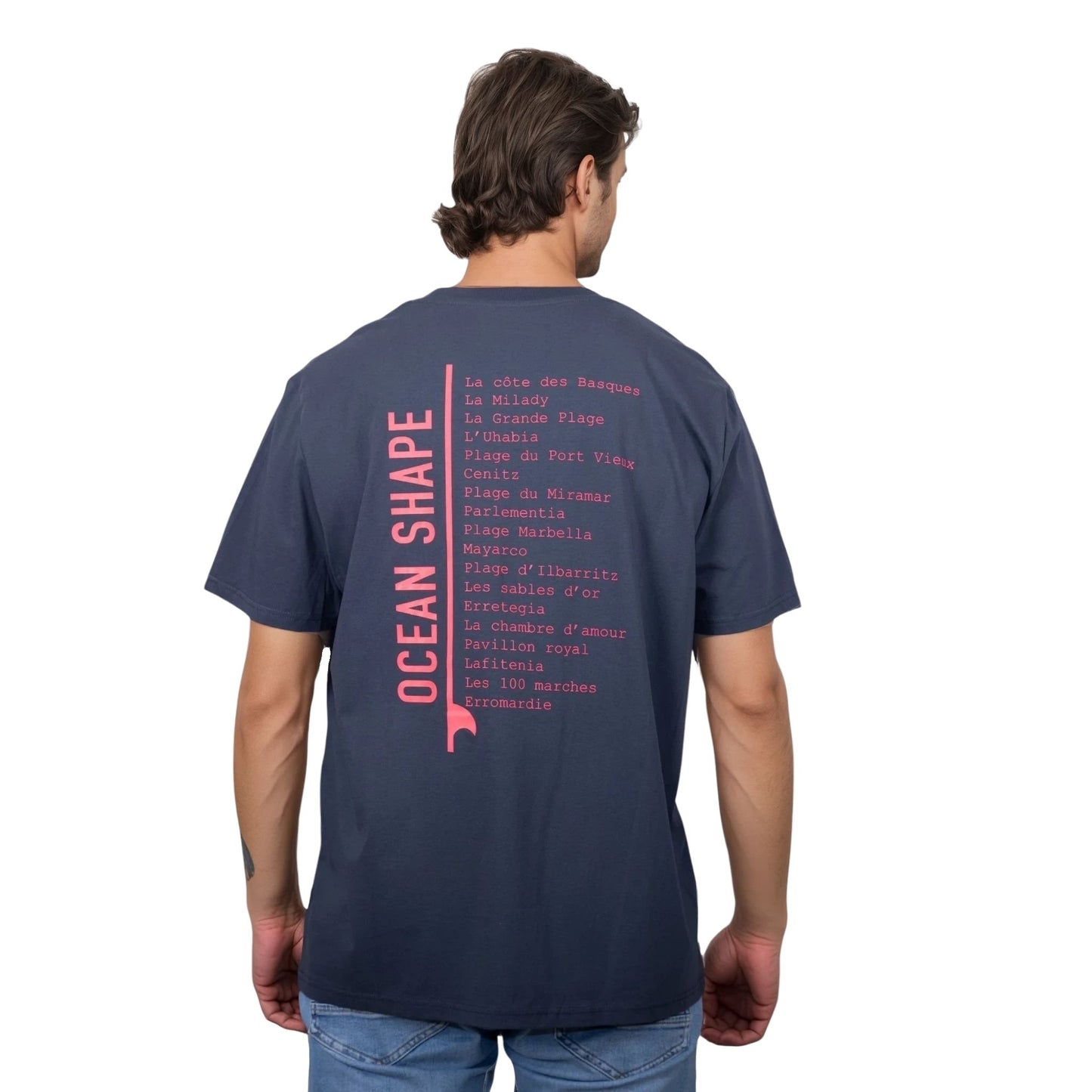 Tee-shirt unisexe gris foncé en coton biologique avec longue liste de plages et grande écriture "ocean shape" rose fluo dans le milieu du dos, vu de dos sur mannequin homme