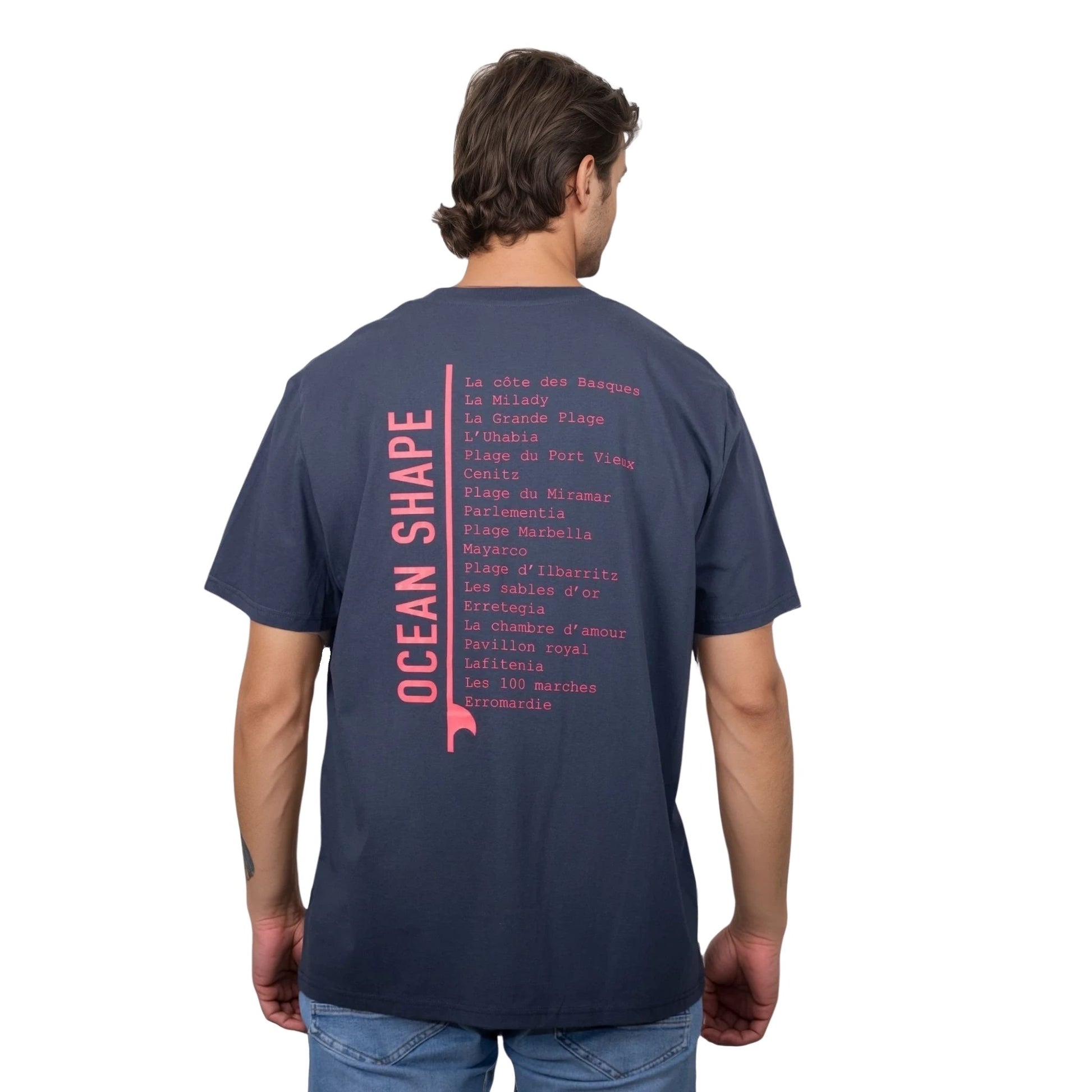 Tee-shirt unisexe gris foncé en coton biologique avec longue liste de plages et grande écriture "ocean shape" rose fluo dans le milieu du dos, vu de dos sur mannequin homme