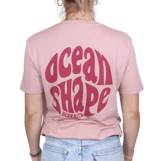 Tee-shirt unisexe rose pale en coton biologique avec gros logo ocean shape Biarritz bubble rose foncé en haut du dos, vu de dos sur mannequin femme