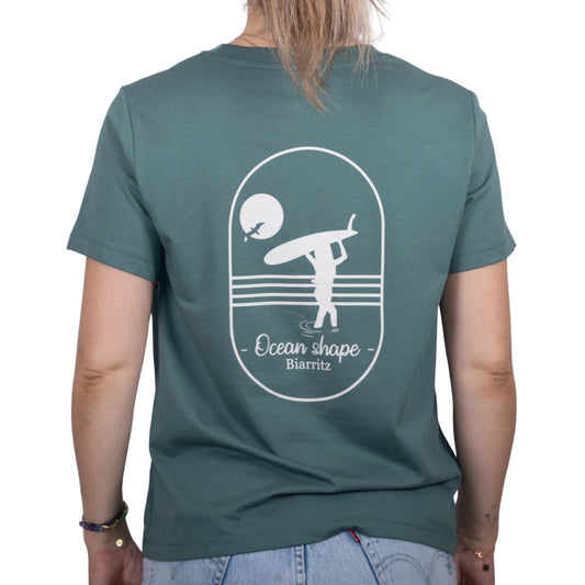 Tee-shirt femme en coton biologique vert sauge avec gros dessin surfeuse qui marche de dos et écriture ocean shape Biarritz écru dans le dos , vu de dos sur mannequin femme 